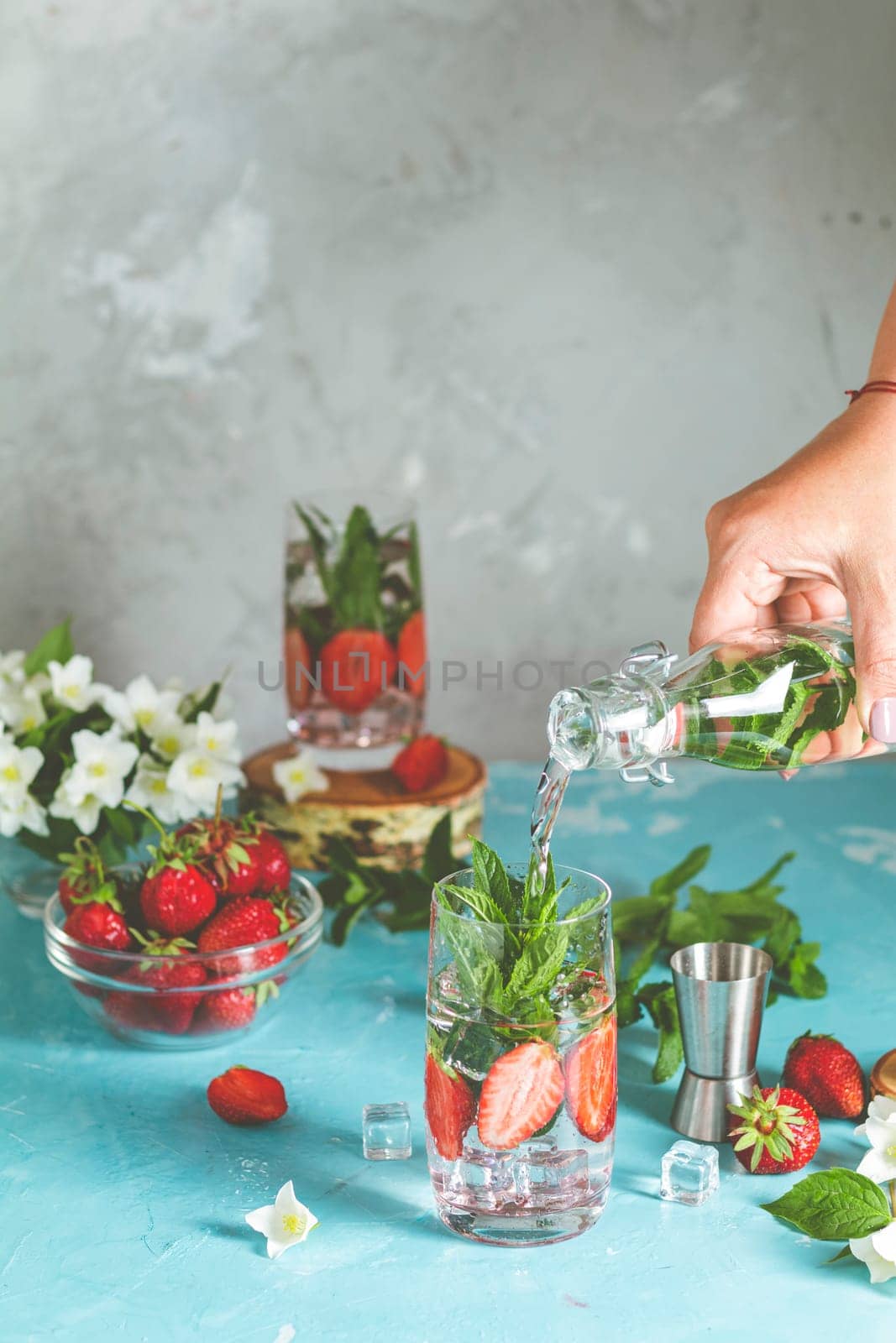 Bartender preparing a refreshing summer drink, mixing strawberries, mint, and ice in a glass for a delicious, thirst quenching experience