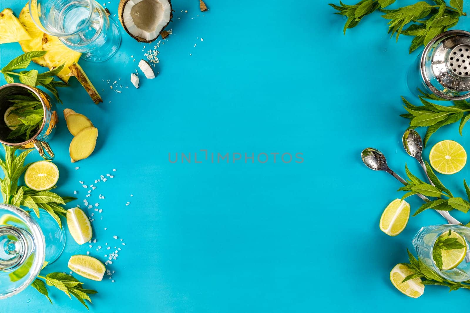 Fresh ingredients like mint, lime, coconut, and pineapple arranged on a vibrant blue backdrop, creating a refreshing scene for cocktail preparation