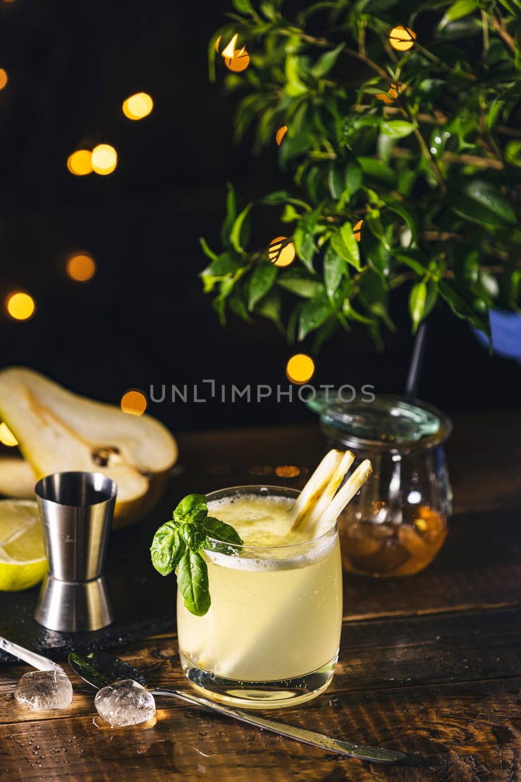 Vibrant pear and basil cocktail, infused with lemongrass, sits on a rustic wooden table, creating a refreshing and inviting scene