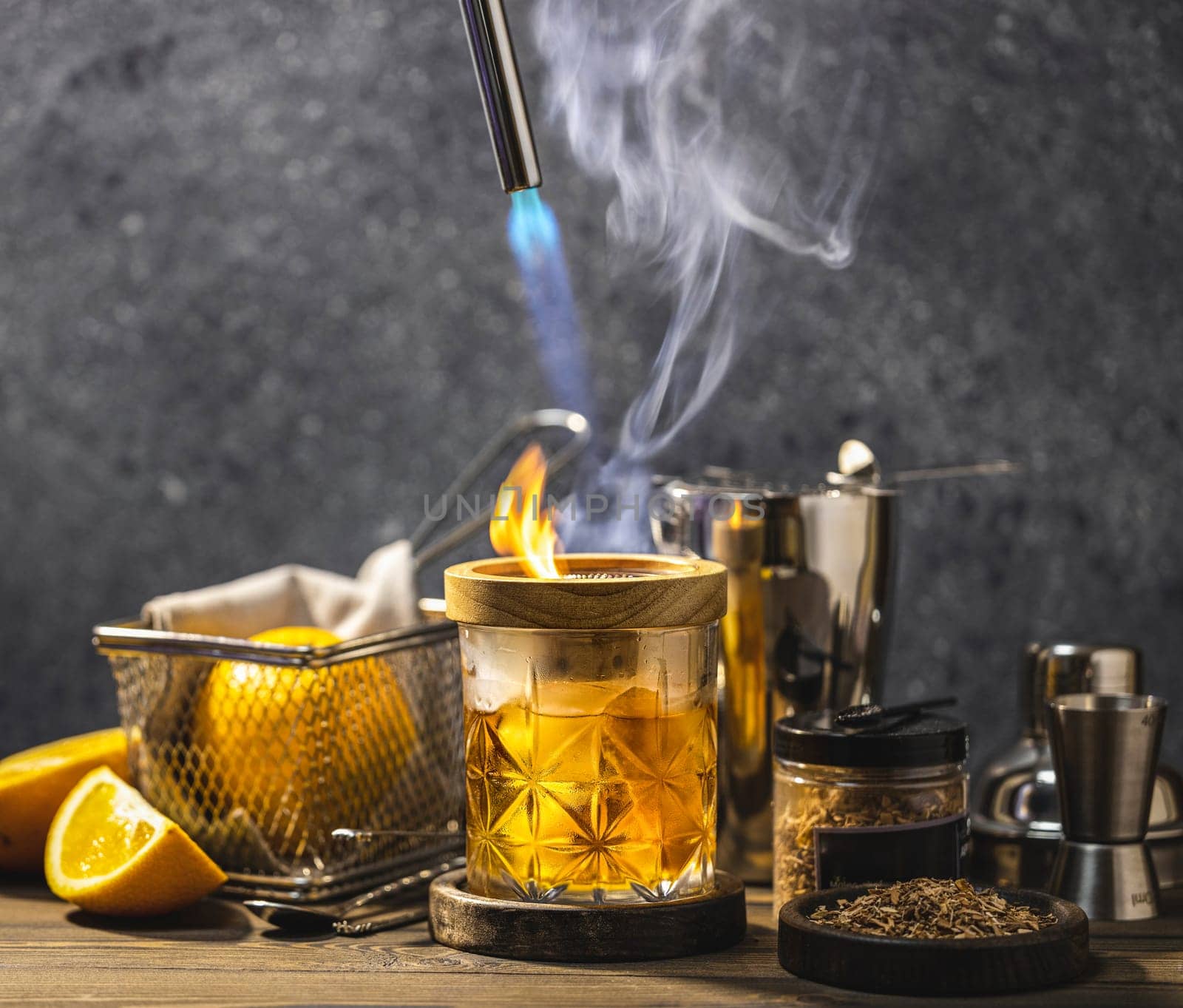 Bartender smoking a cocktail in an elegant glass with orange slices and bar equipment creating a visually appealing drink