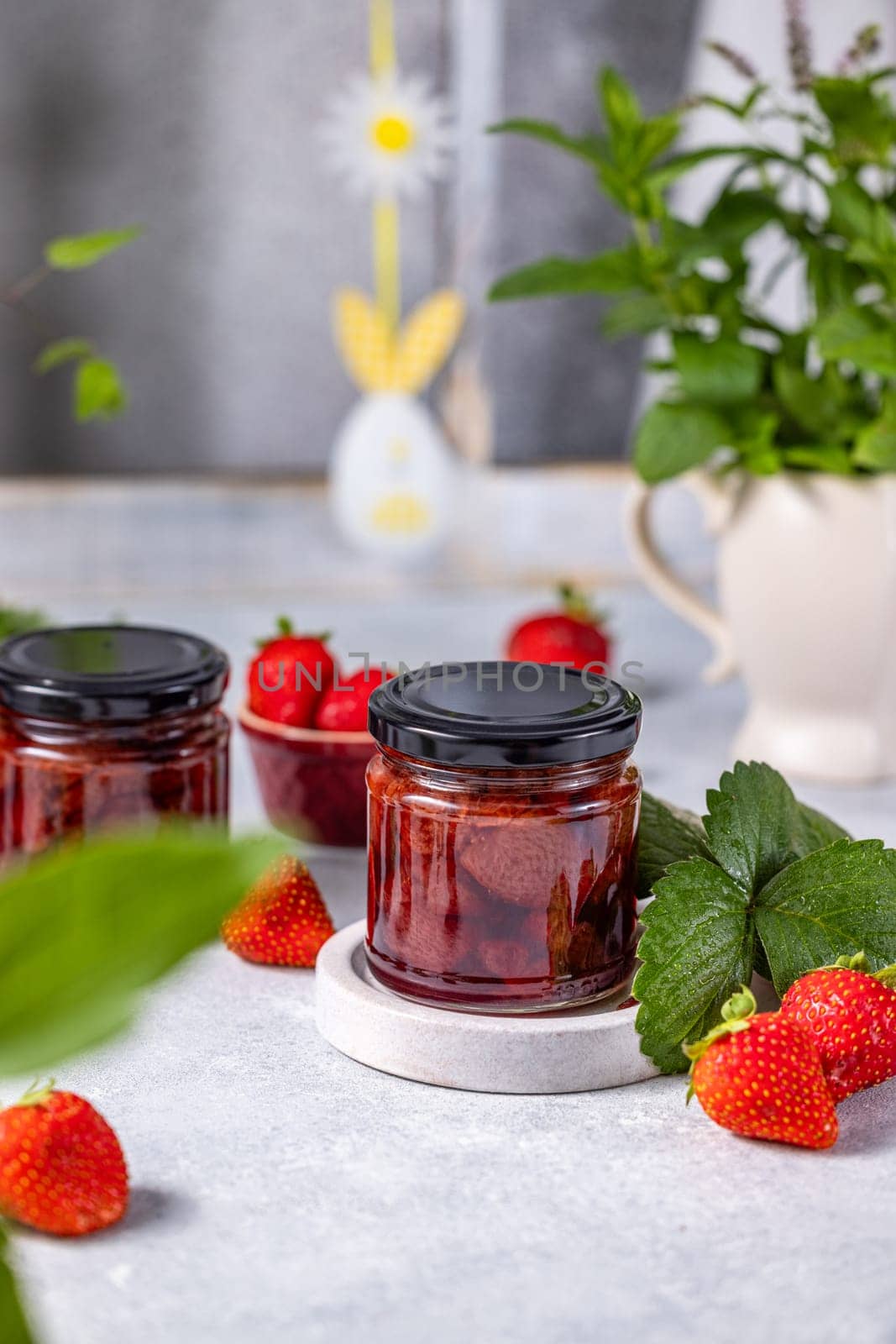 Glass jars with delicious homemade strawberry jam, preserving the taste of summer with fresh, ripe strawberries