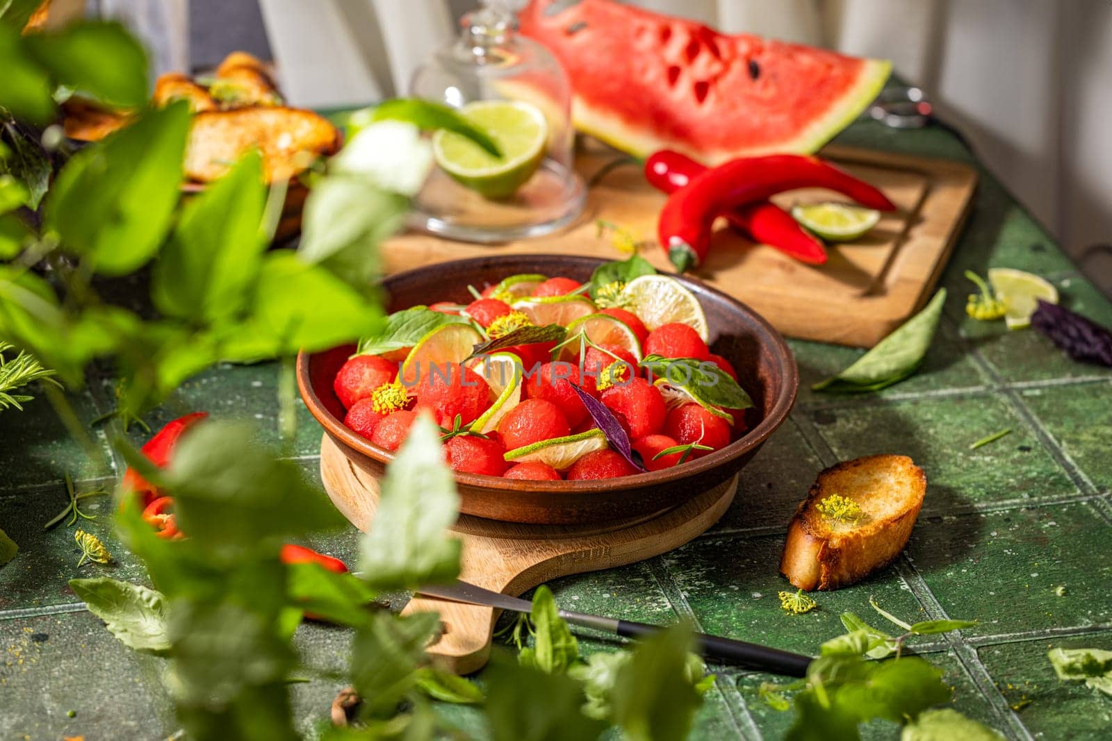 Refreshing watermelon salad with lime, basil, and edible flowers, served in a rustic bowl on a green table, perfect for a summer meal