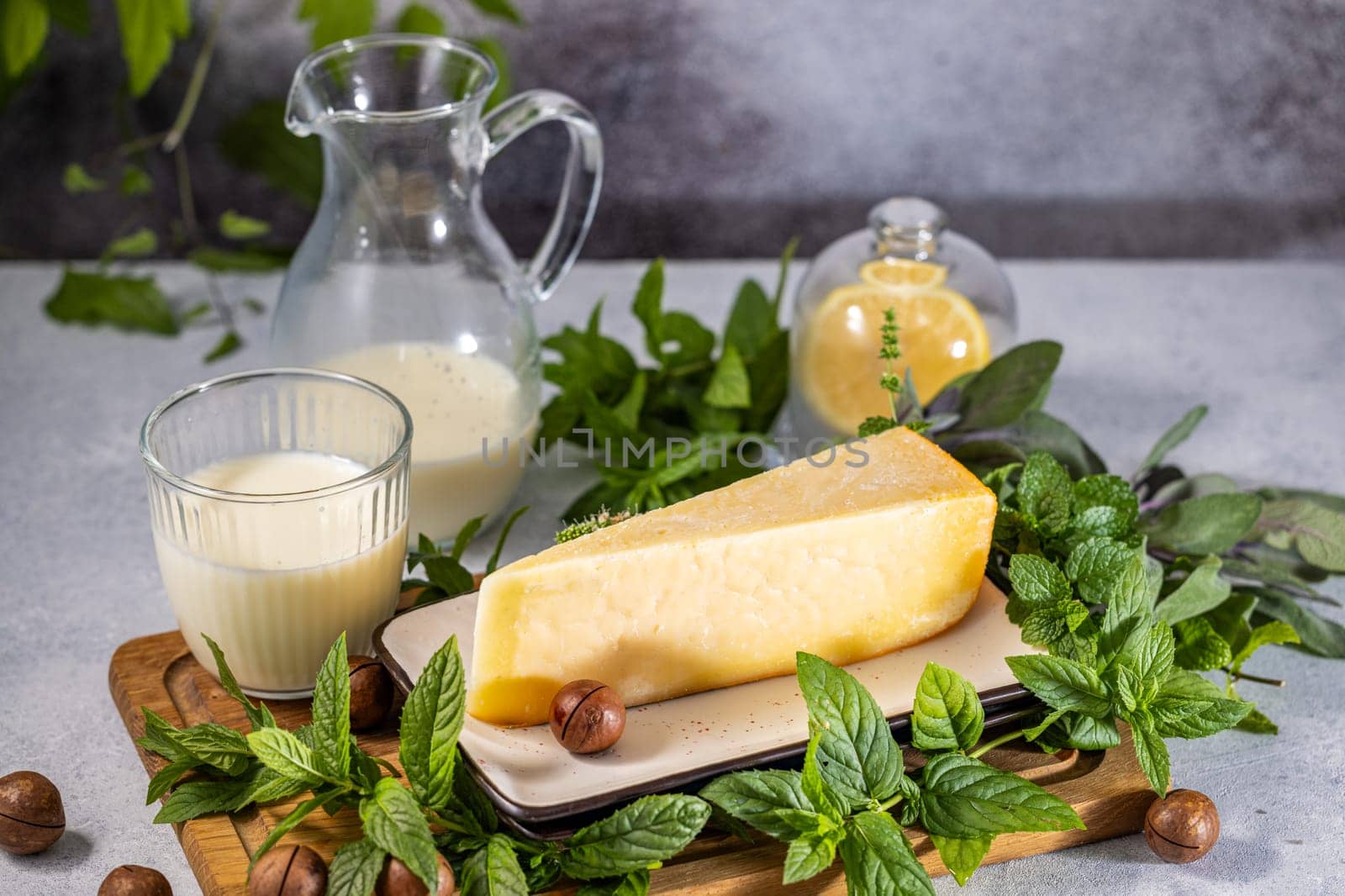 Parmesan cheese with milk, mint, macadamia nuts, and lemon on a wooden board, creating a fresh and flavorful culinary scene