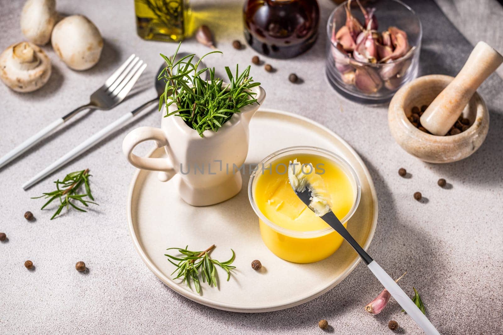 Preparing a meal with ghee butter, fresh rosemary, garlic, mushrooms, peppercorns, and olive oil