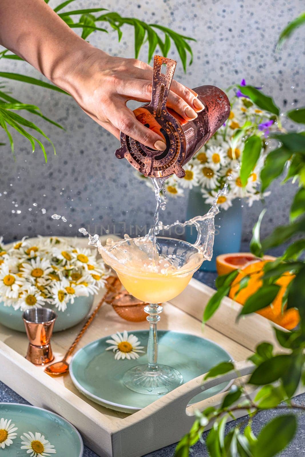 Bartender skillfully pours a refreshing cocktail into a stylish glass, causing a splash and adding a touch of excitement to the drink preparation
