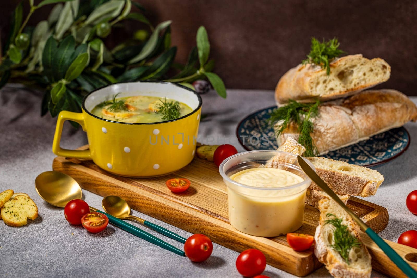 Delicious creamy soup with croutons, fresh baguette with cheese sauce, and cherry tomatoes, creating a flavorful and inviting meal