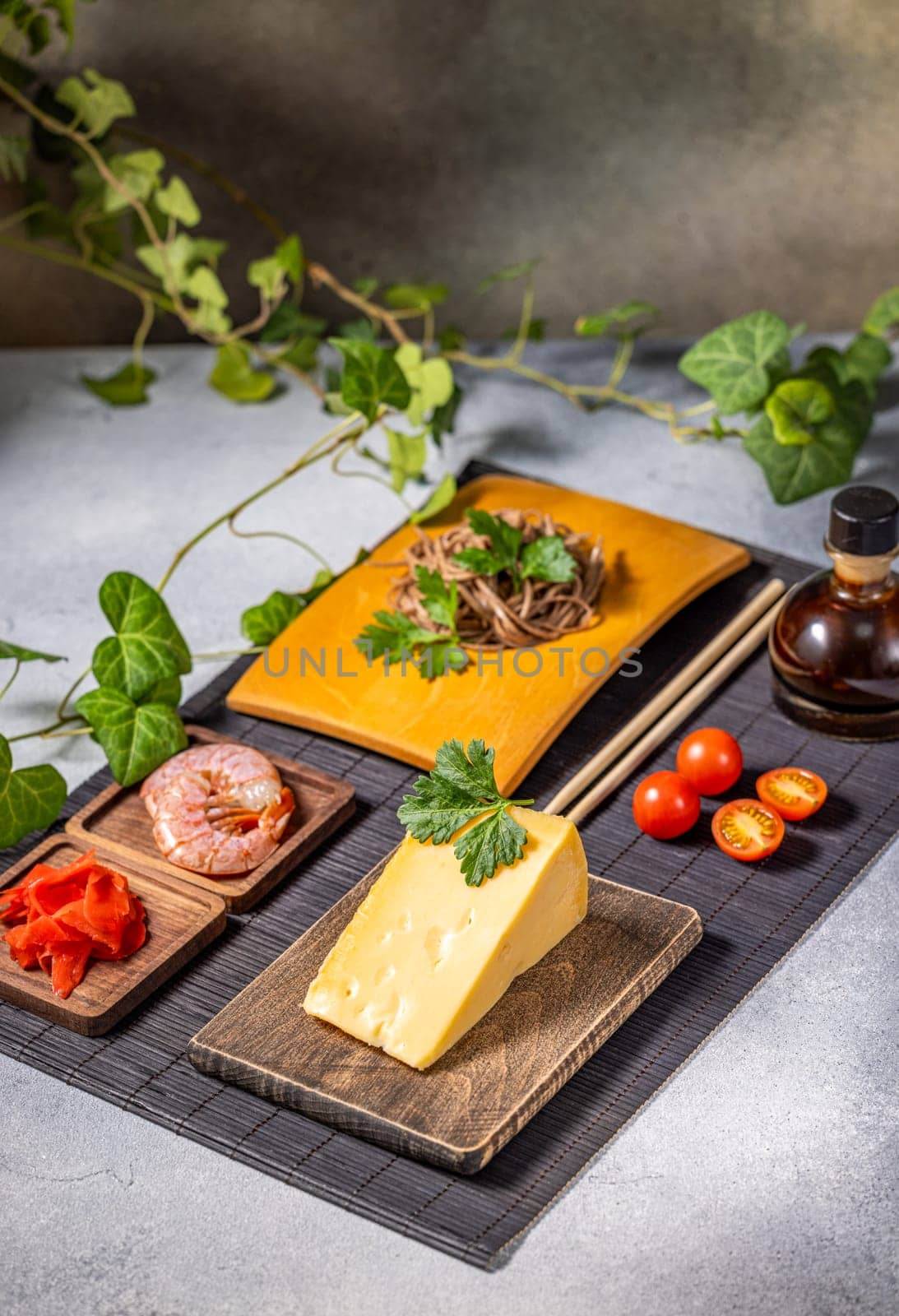 Soba noodles, cheese, shrimp, and cherry tomatoes are arranged on a table, showcasing a unique fusion of culinary traditions