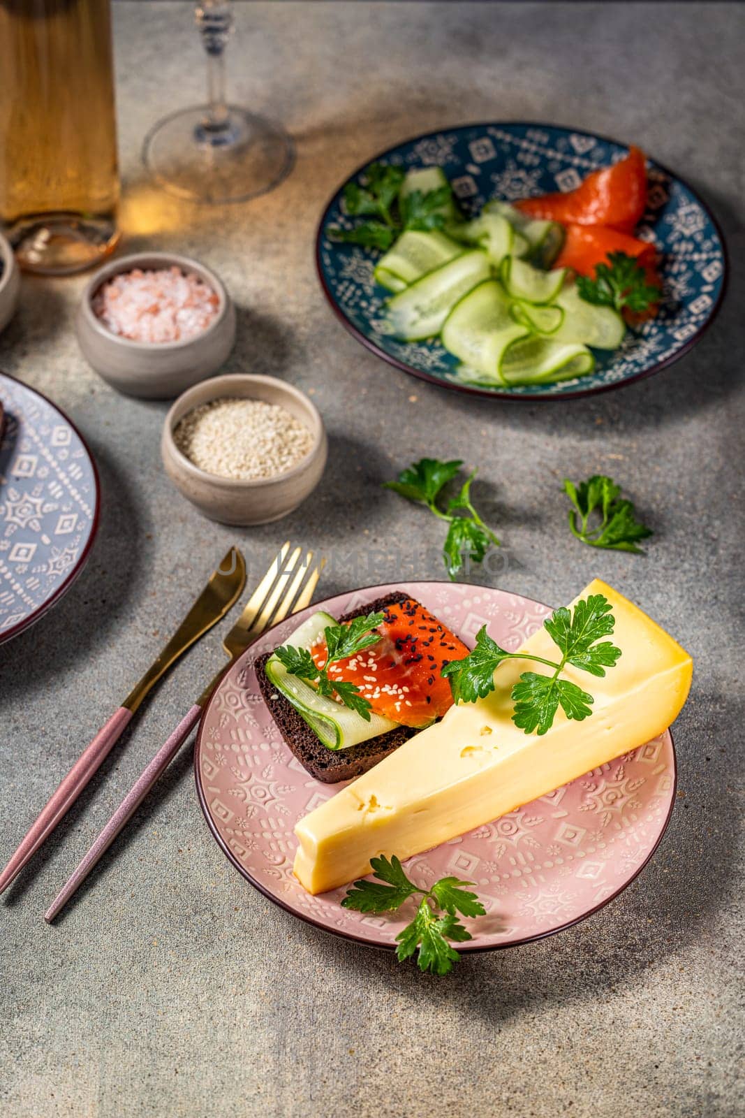 Elegant appetizer featuring smoked salmon, cucumber, and a slice of cheese served on rye bread, accompanied by fresh herbs