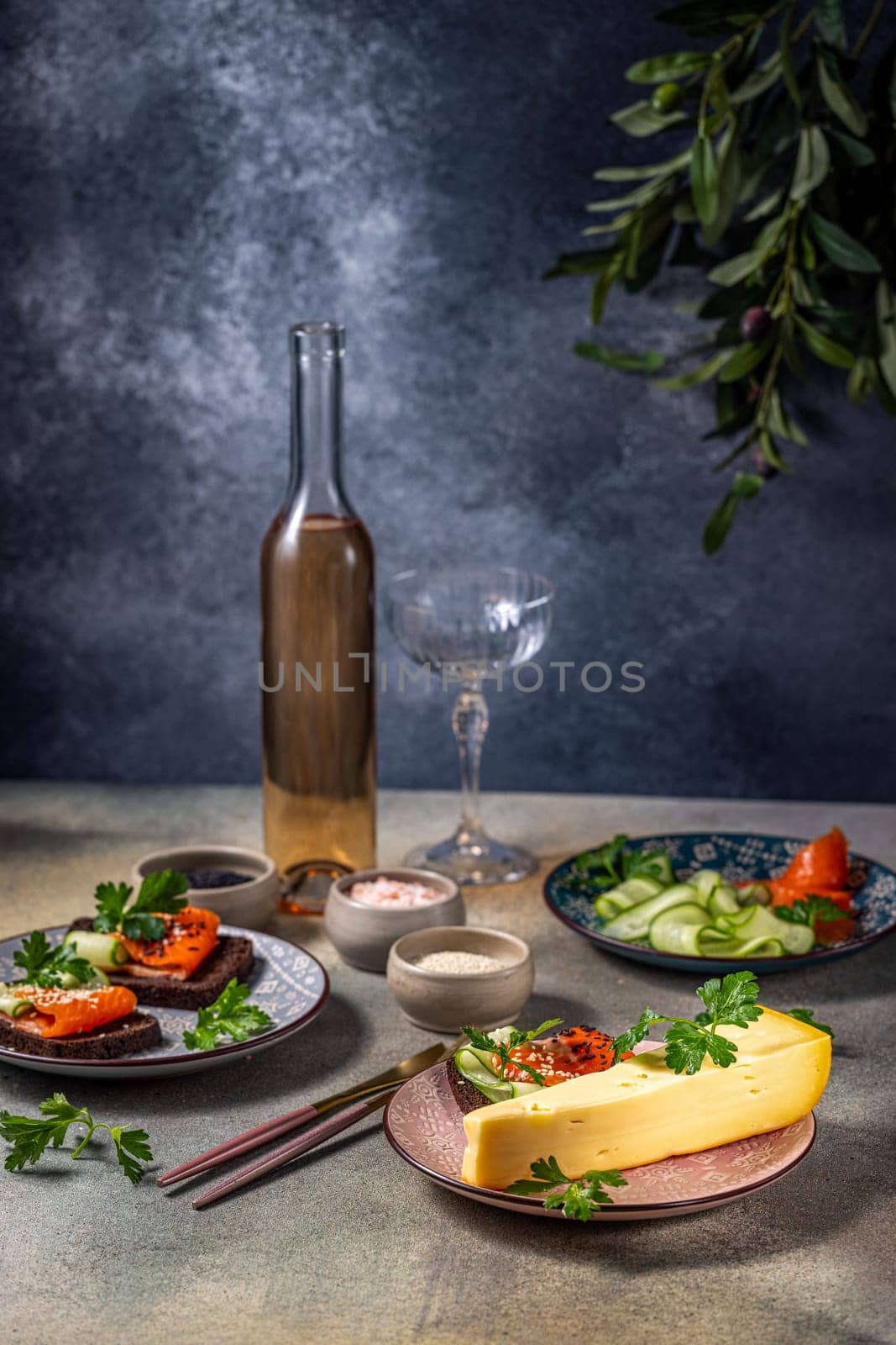 Smoked salmon, cheese, cucumber sandwiches are being prepared for a romantic dinner with rose wine on a decorated table