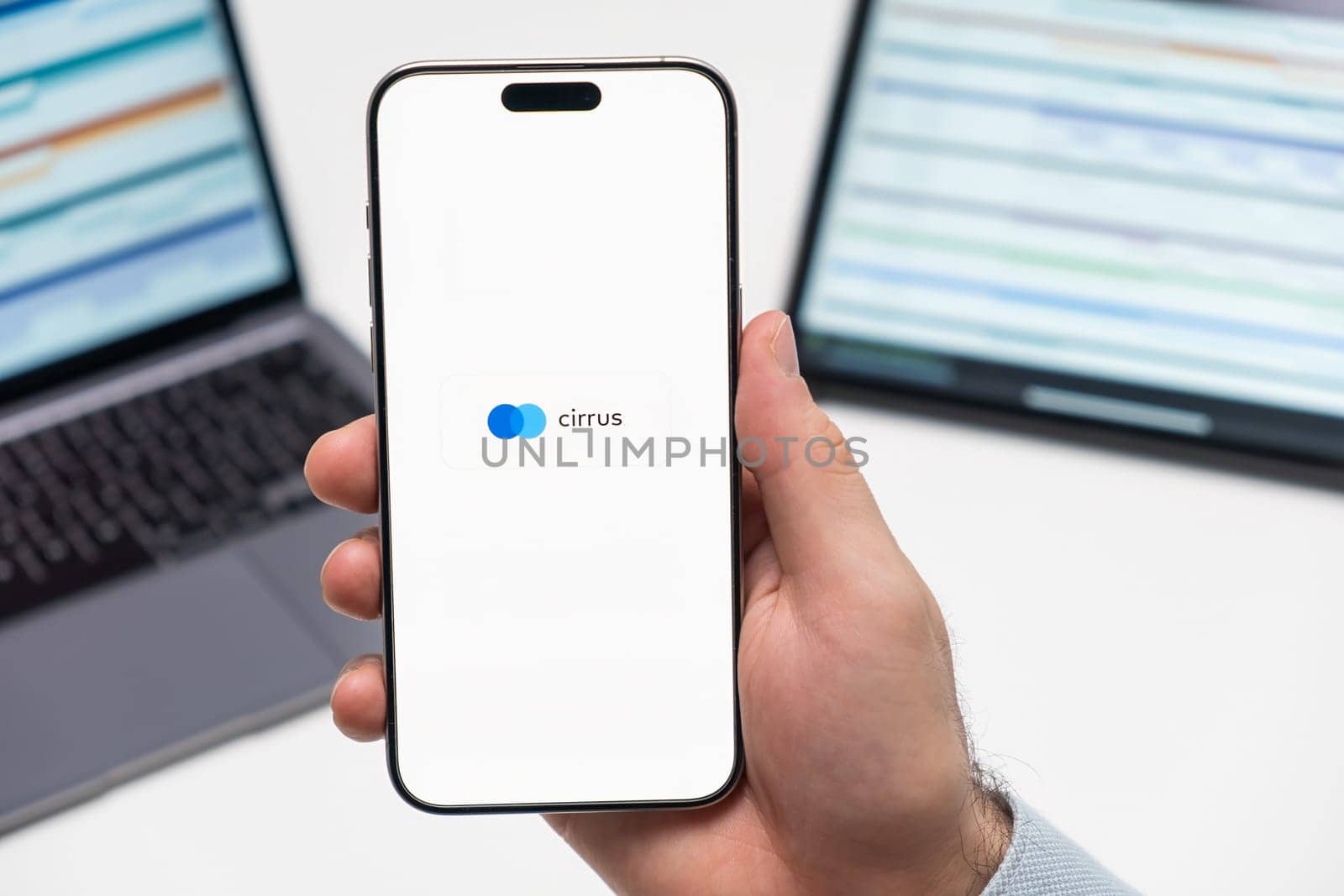 PRAGUE, CZECH REPUBLIC - JANUARY 21 2024: Cirrus logo on the screen of smartphone in mans hand on the workplace background.