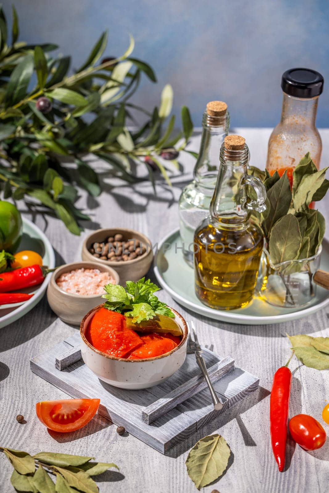 Delicious red peppers are waiting to be tasted, accompanied by fresh herbs, spices, and high-quality olive oil