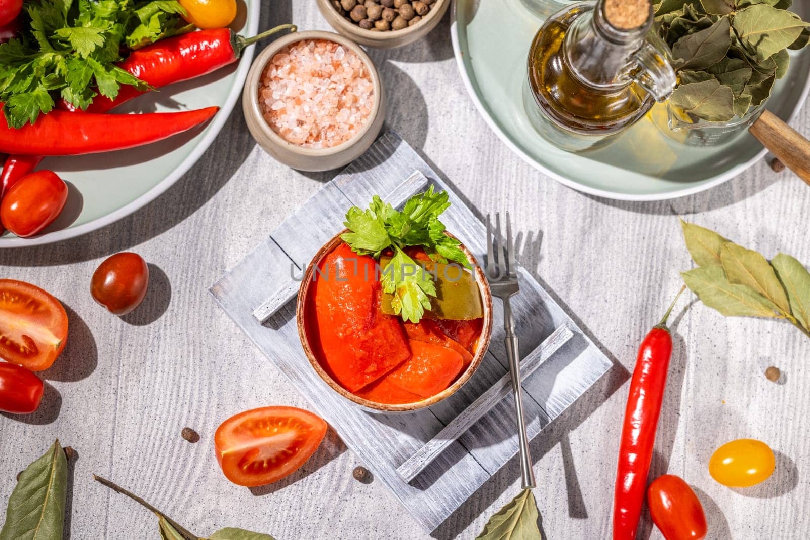 Delicious pickled red bell peppers served with fresh tomatoes, herbs, spices, and olive oil, creating a vibrant culinary scene