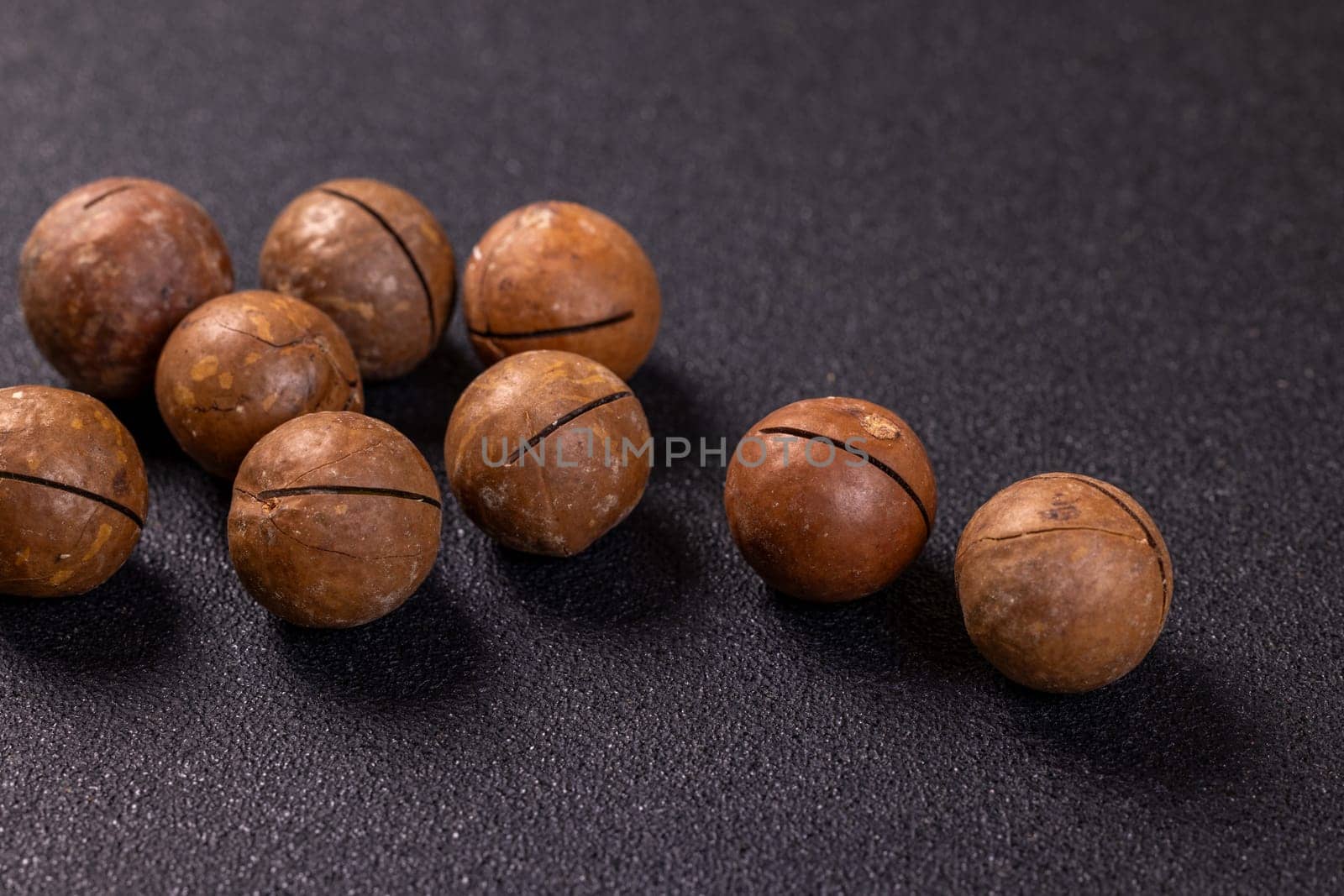 Shelled macadamia nuts resting on a dark surface, creating a visually appealing arrangement for snack enthusiasts