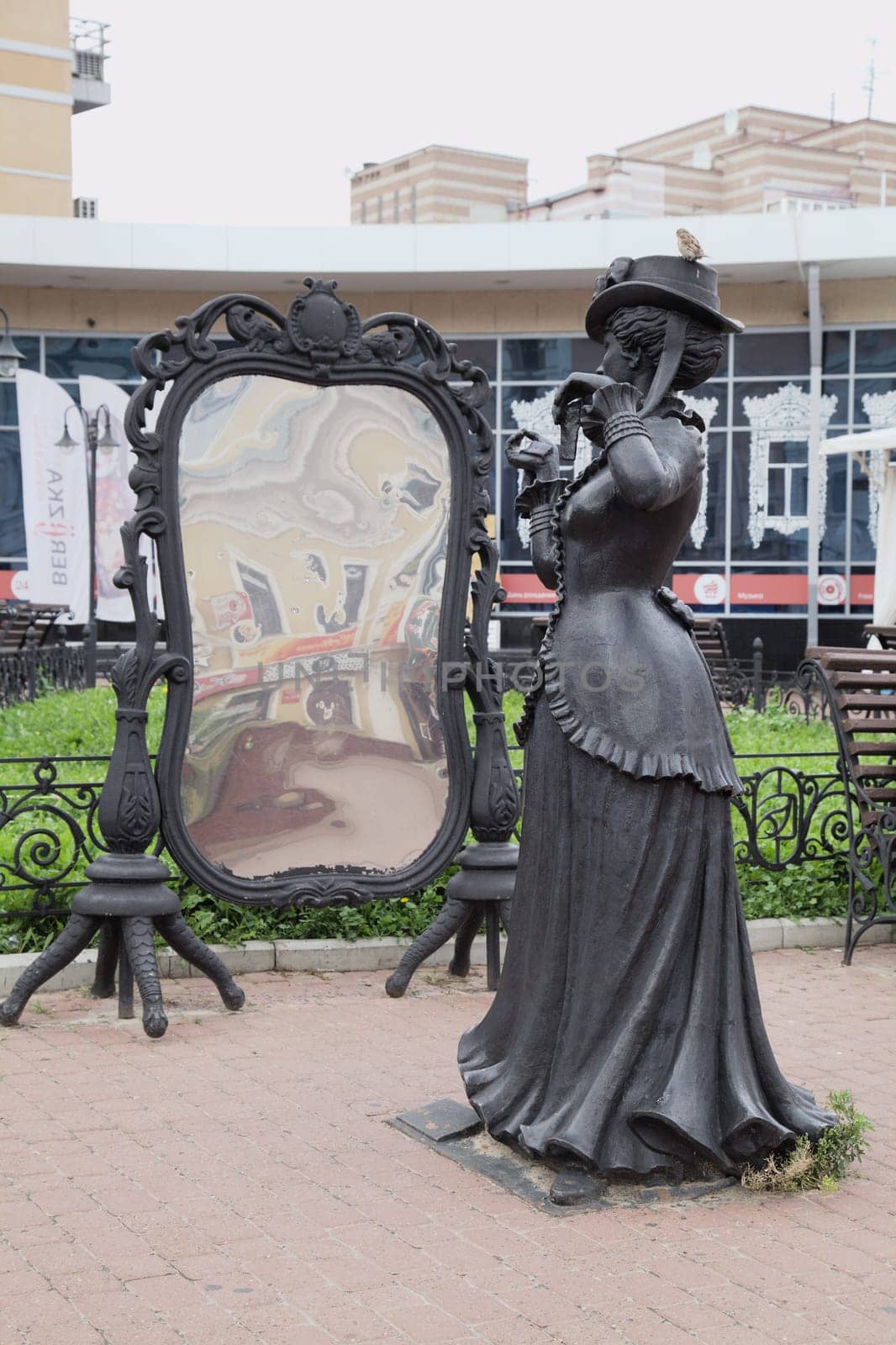 Nizhny Novgorod, Russia - August 27, 2016 - Street sculpture depicting a lady in historic attire next to a large ornate mirror