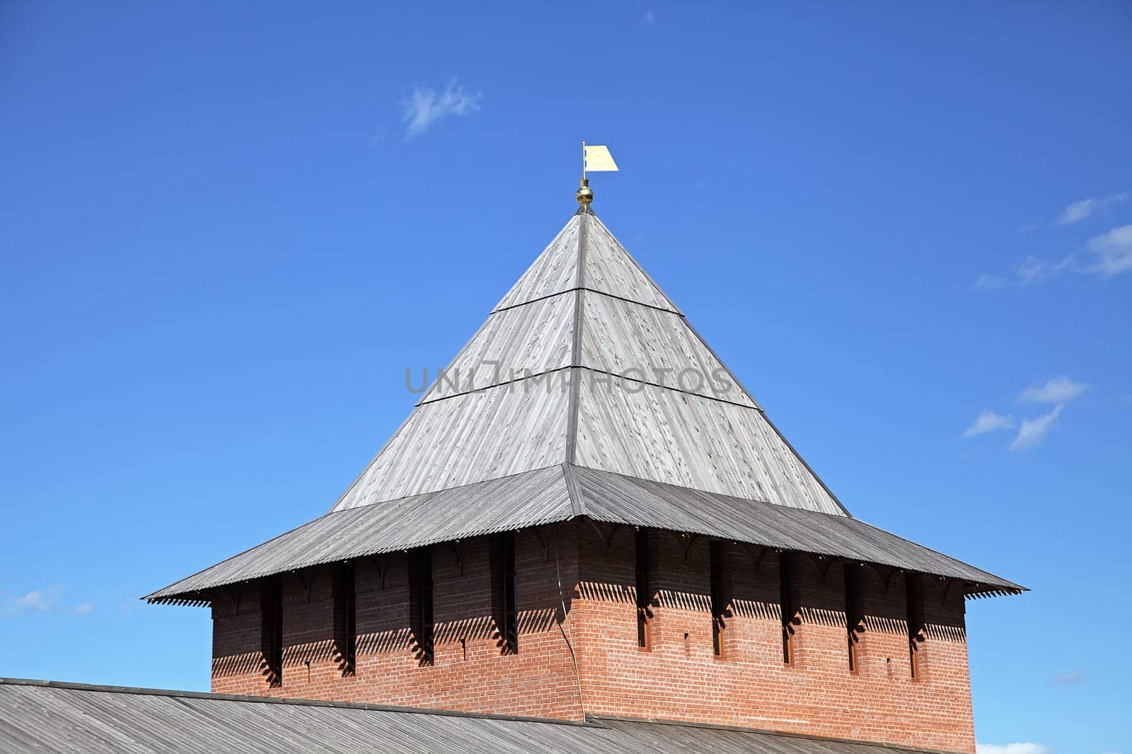 The wooden roof of a historic tower in Nizhny Novgorod kremlin is beautifully illuminated under the bright sky.