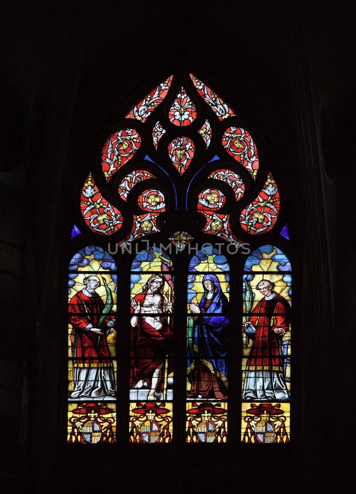Stained glass window with vibrant colors and religious figures in Toulouse's Cathedral Saint-Etienne.