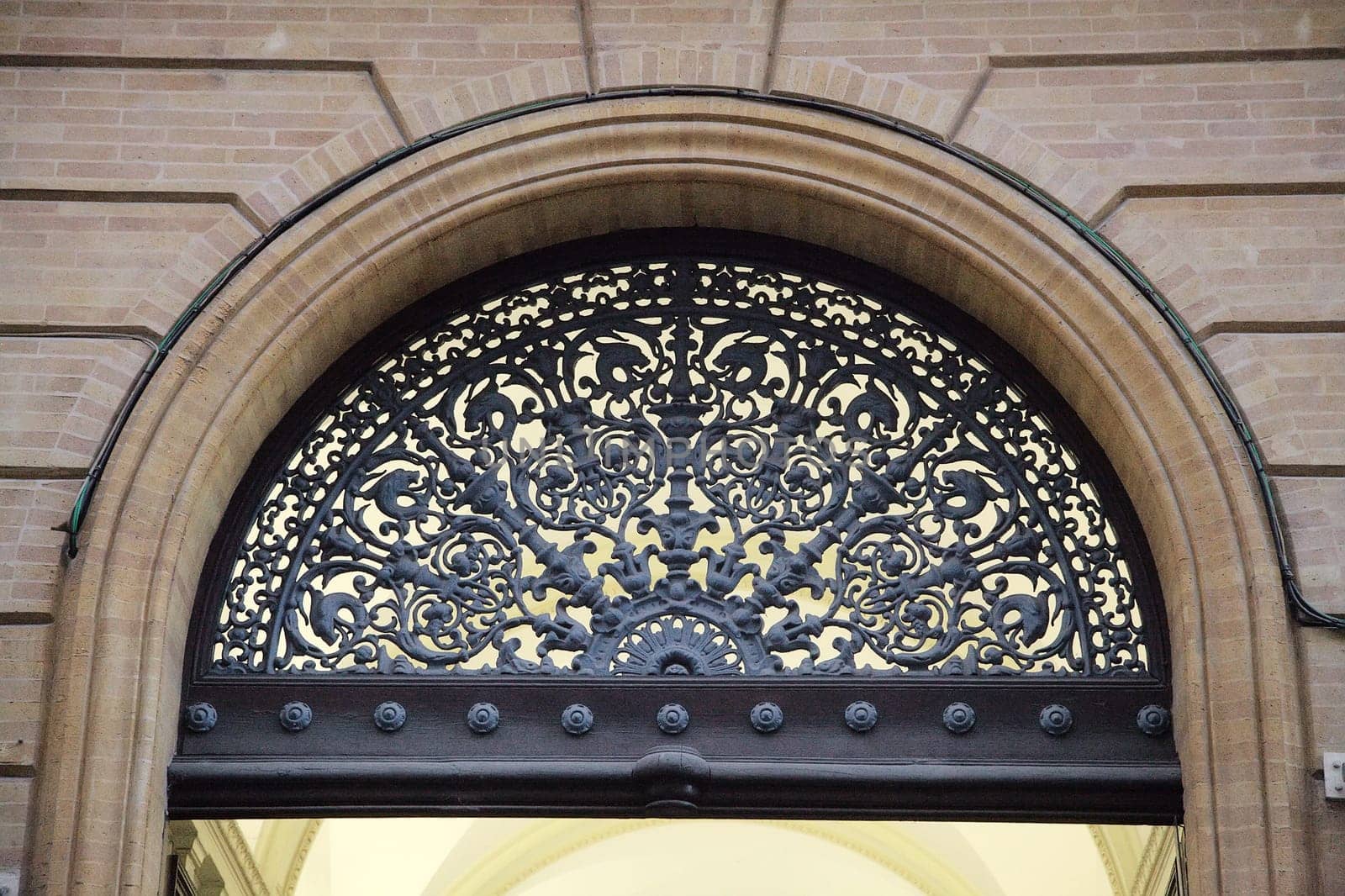 Ornate ironwork adorns an archway in Toulouse, highlighting the city's rich architectural heritage.