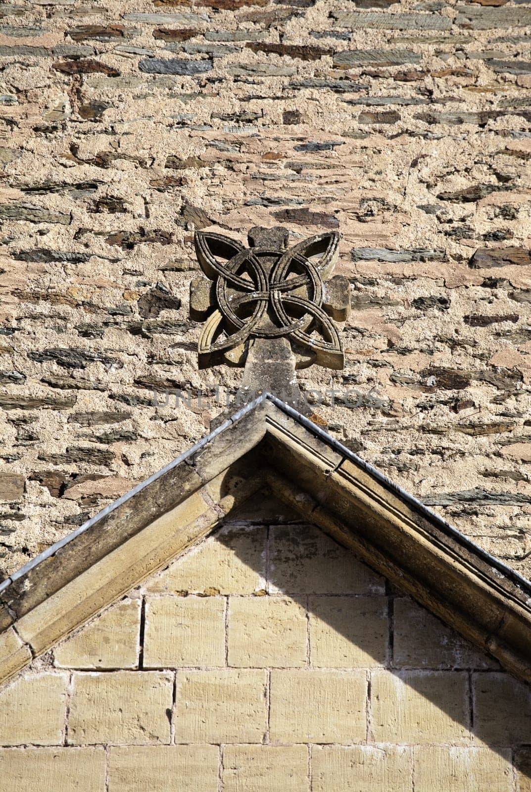 Unique stone sculpture adorns the gabled roof of a historic structure in Conques, showcasing exquisite craftsmanship.