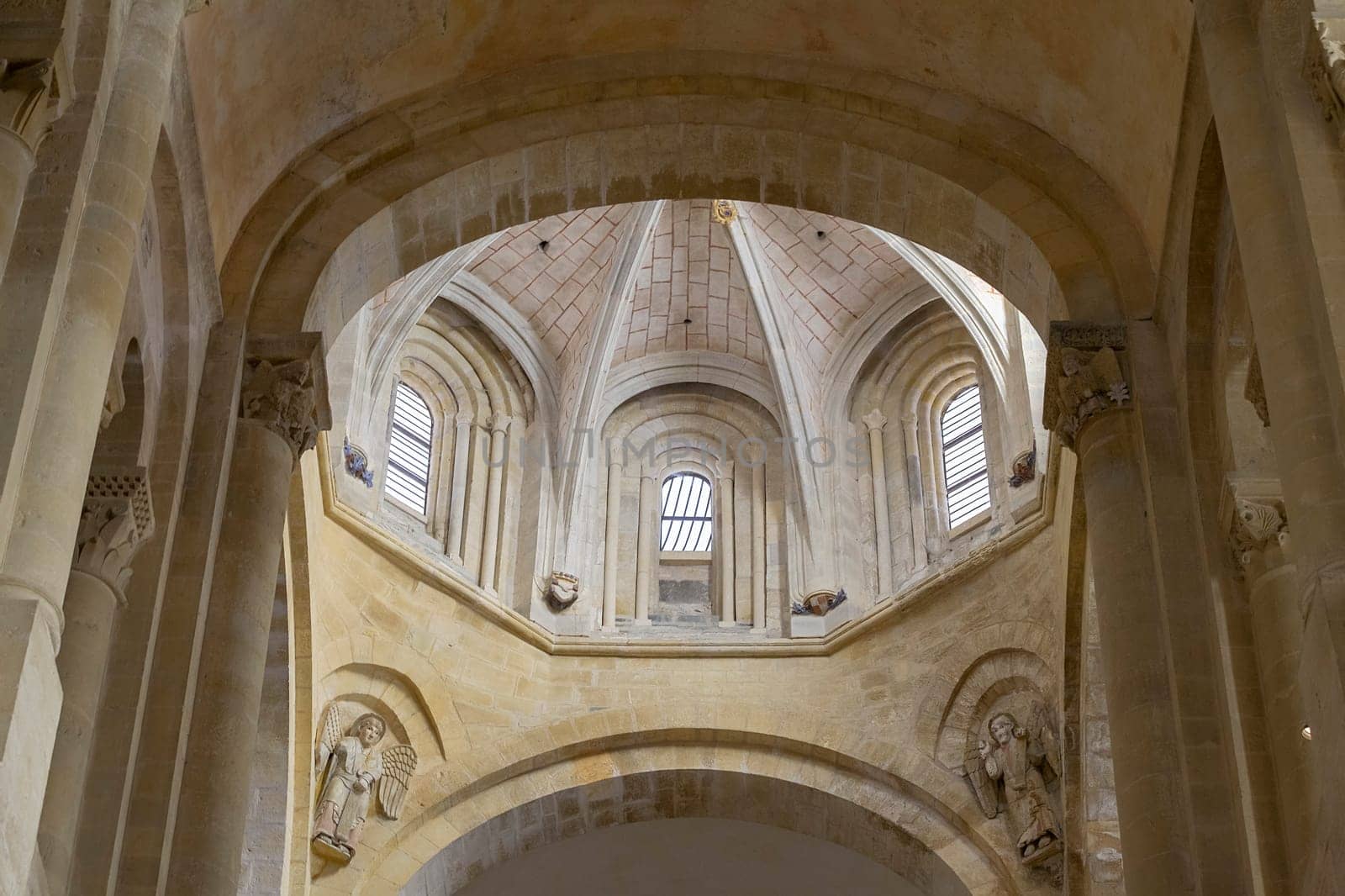 Explore the stunning interior of a Gothic church in Conques, France featuring elaborate stone arches and serene light.