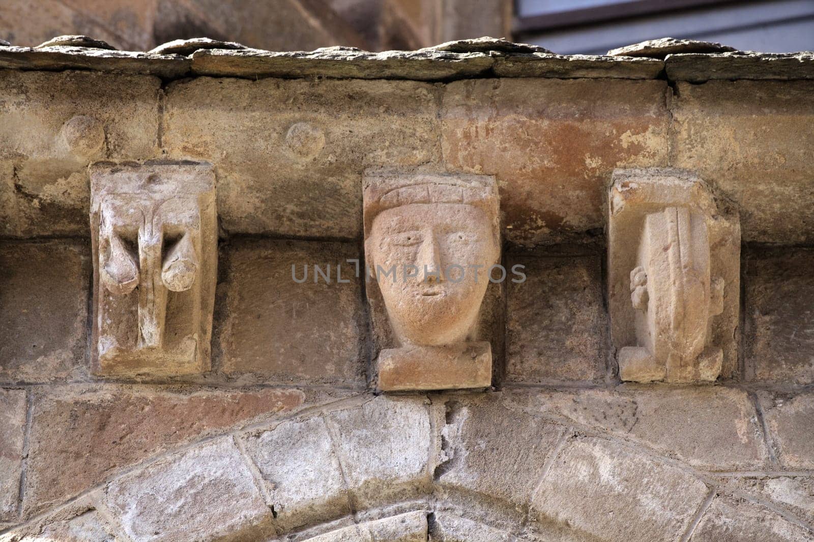 Intricate stone carvings decorate the exterior of an ancient structure in Conques, revealing the artistry of the era.
