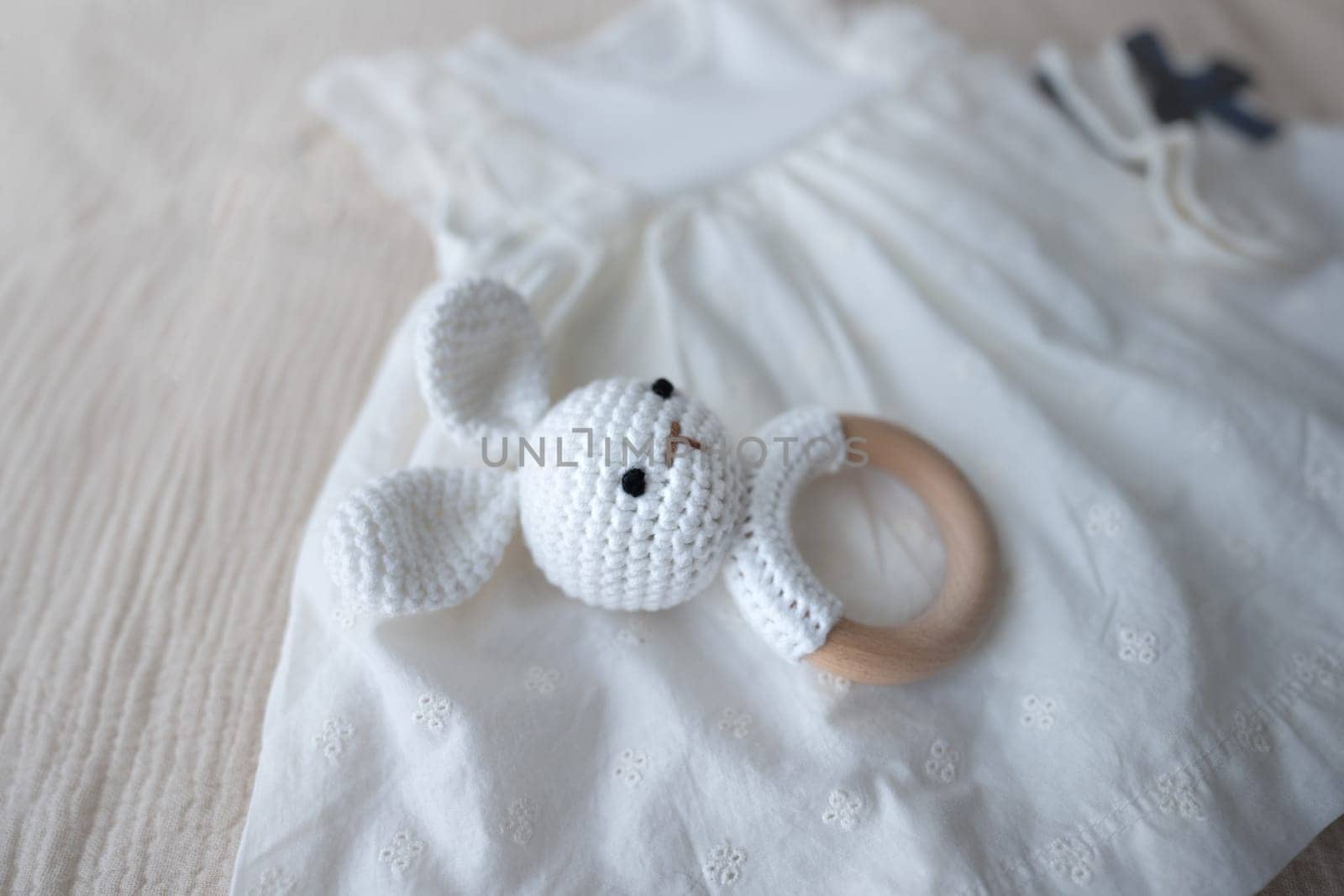 Composition with white baby clothes, accessories and toys on brown background. Newborn bodysuit and mittens. Baby essentials and motherhood concept. High quality photo