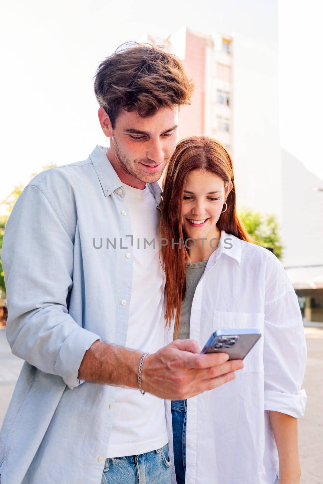 man and woman smiling happy looking a cell phone together, they are enjoying the moment and sharing something on the phone, concept of technology of communication and social media