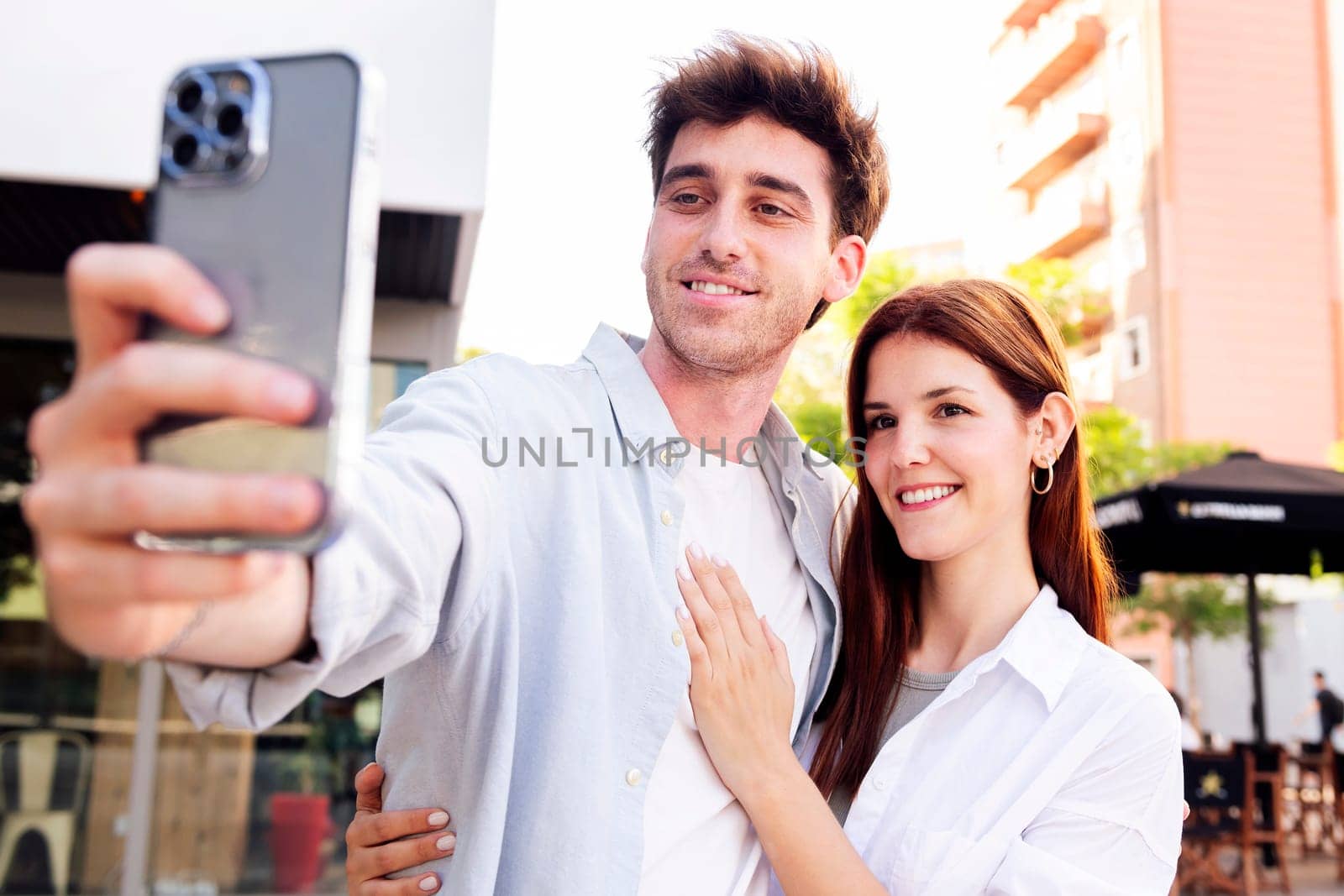 man and woman smiling happy taking a selfie together, the man is holding a cell phone and the woman is smiling, scene is happy and lighthearted