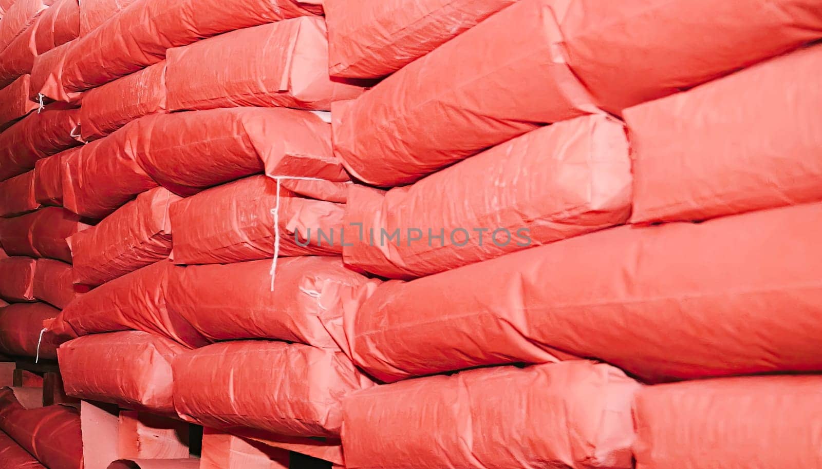 Rows of neatly arranged red bags stacked high in a spacious warehouse setting with warm lighting highlighting the storage area.