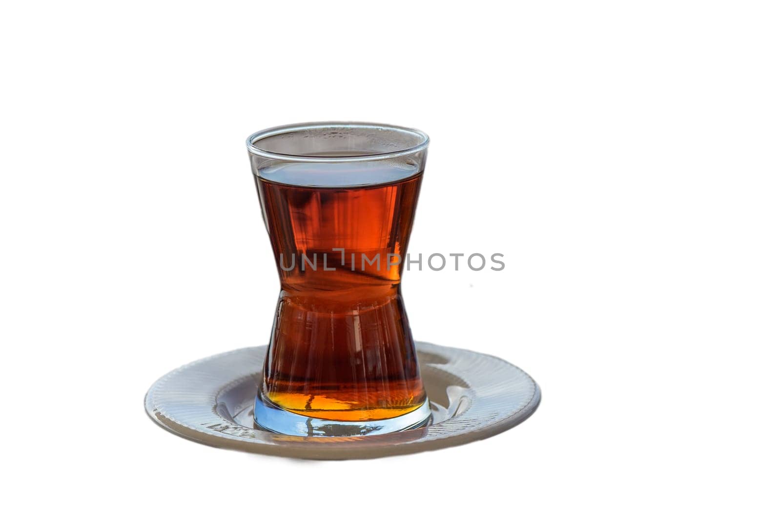 A beautifully crafted glass holds aromatic tea, resting on an elegant dish, inviting relaxation and warmth.