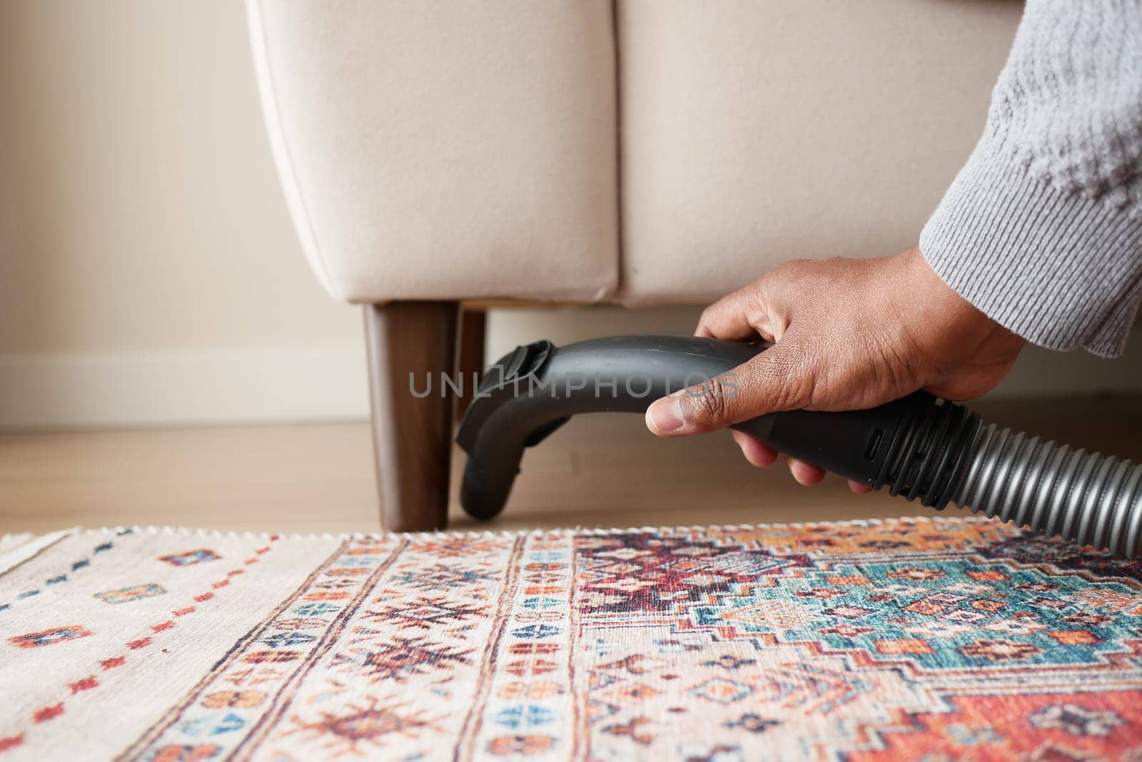 Cleaning under furniture with a vacuum in a stylish living area.