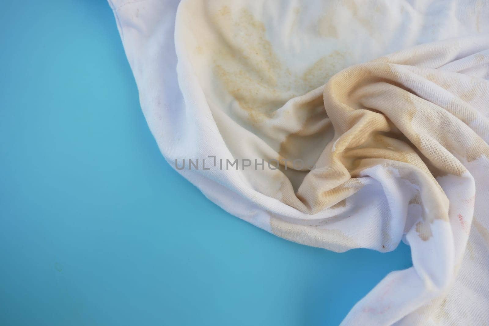A dirty cloth with stains lies on a vibrant blue background, revealing wear.