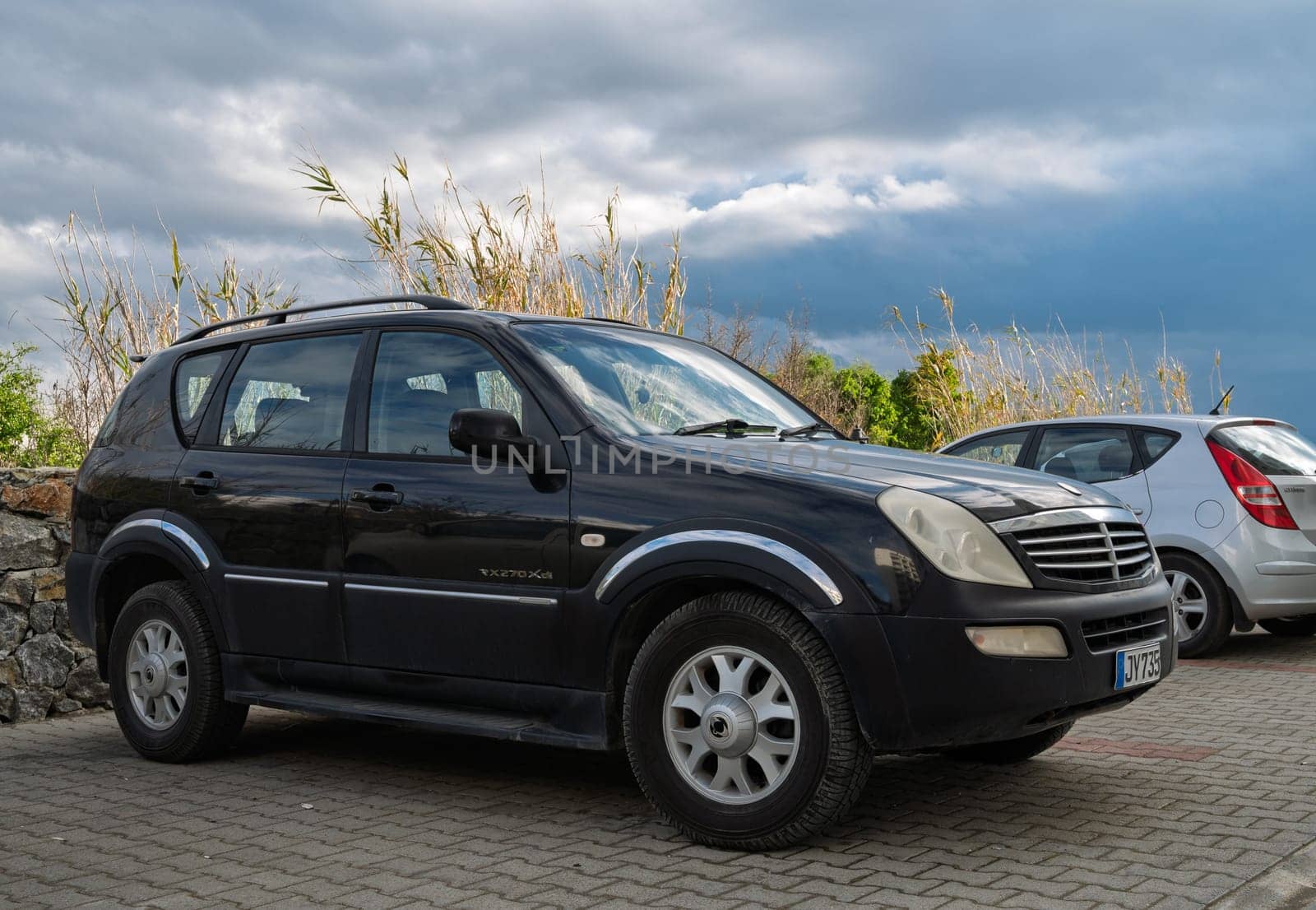Gaziveren Cyprus -28.02.2025 A sleek black SUV stands parked beside a silver compact car against a backdrop of moody, overcast skies.