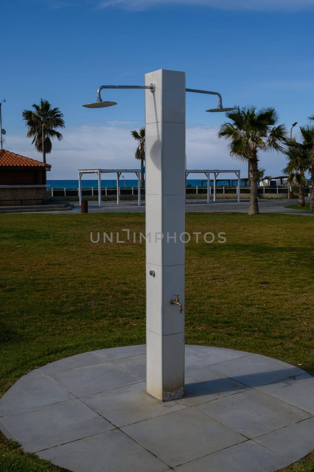 A simple outdoor shower stands in a grassy area, inviting beachgoers to rinse off after enjoying the sun and surf.