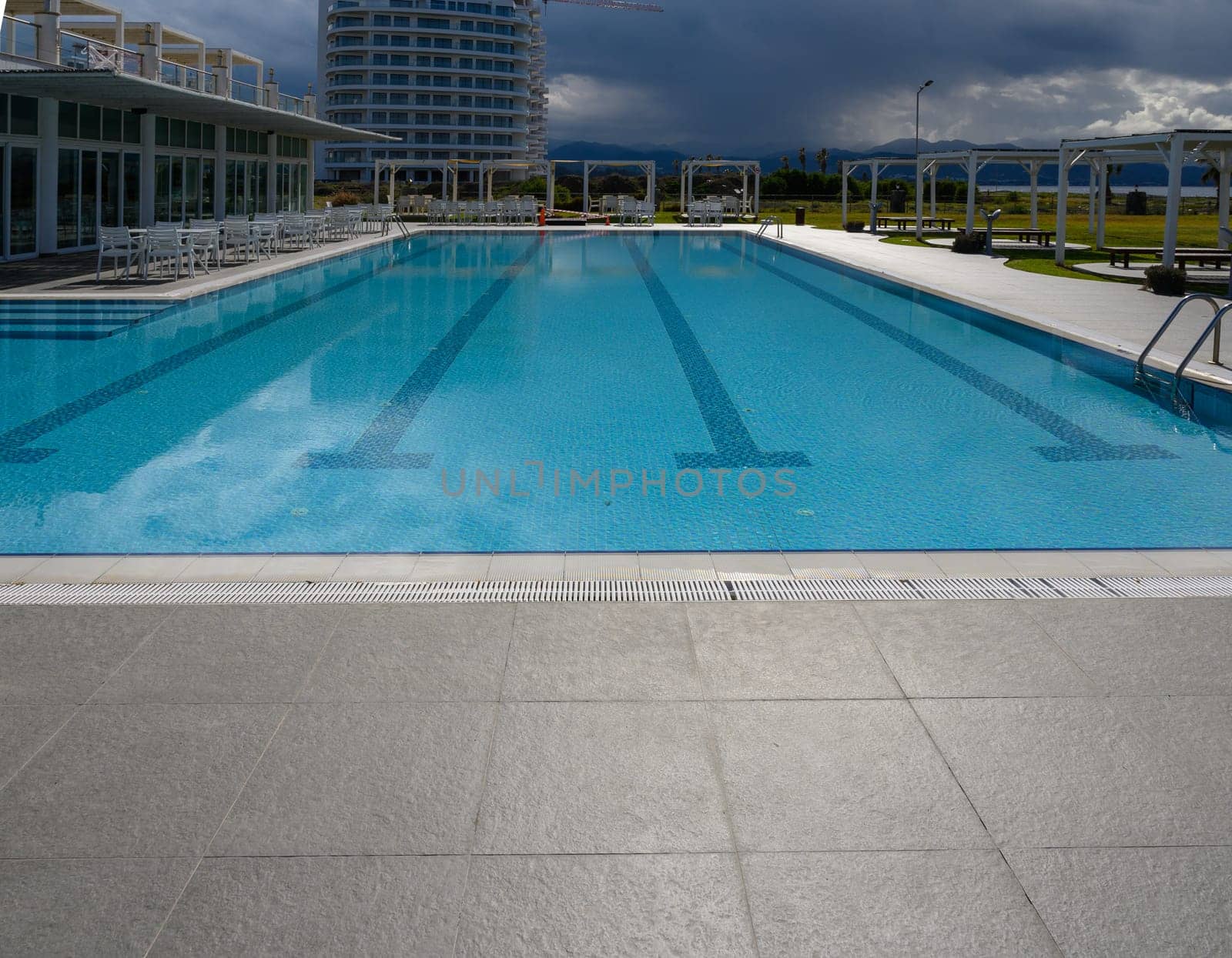 Refreshing waters shimmer at a contemporary resort, set against a backdrop of sweeping clouds and distant mountains.