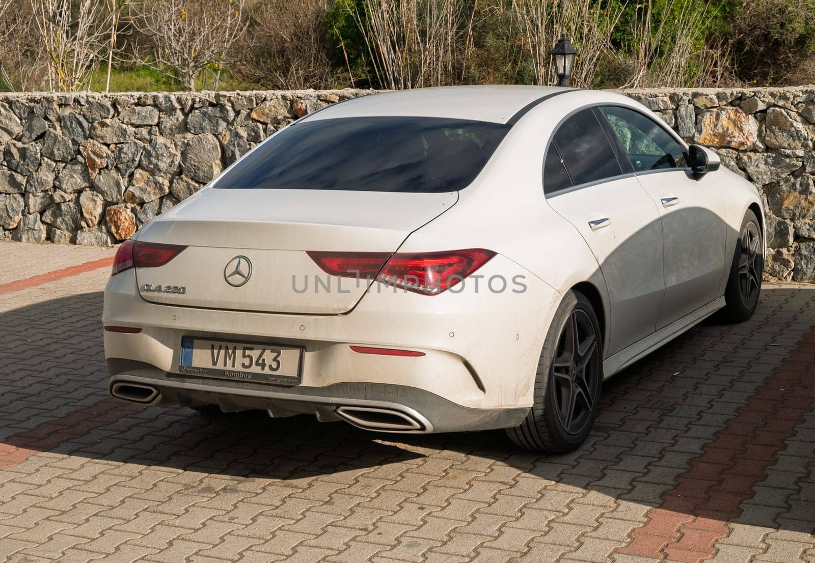Gaziveren Cyprus -28.02.2025 A sleek luxury sedan sits quietly among nature, showcasing its elegant design and subtle dust under sunny skies.