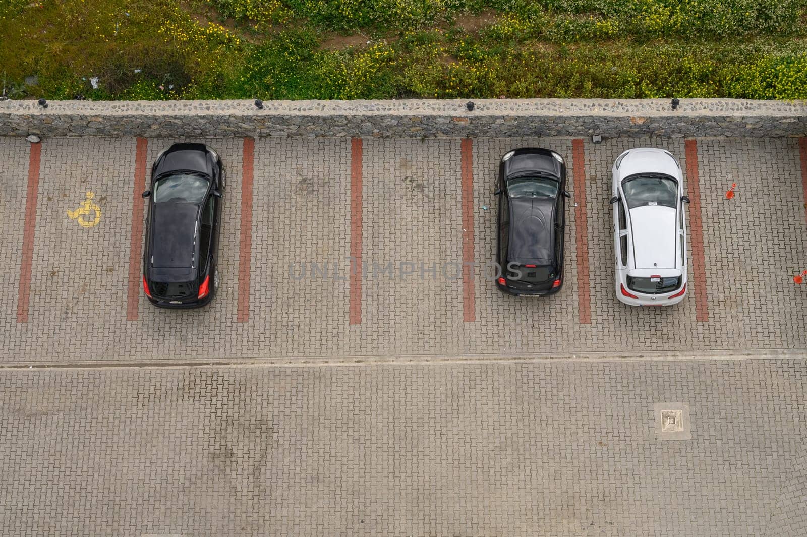 Gaziveren Cyprus -01.03.2025 Vehicles are neatly parked in a patterned layout next to a grassy area under an overcast sky.
