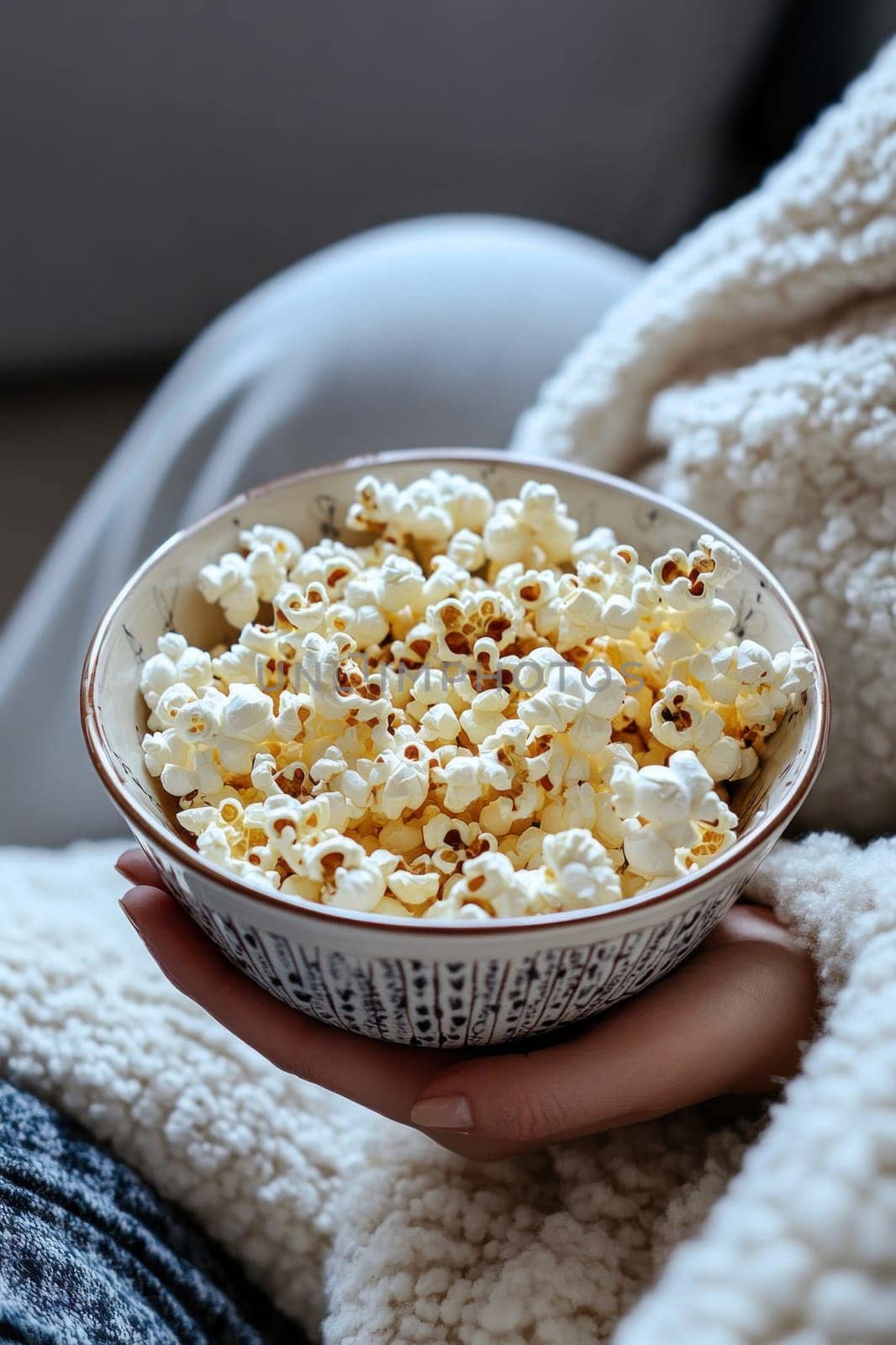 Woman relaxing on sofa with bowl of popcorn, enjoying movie night at home