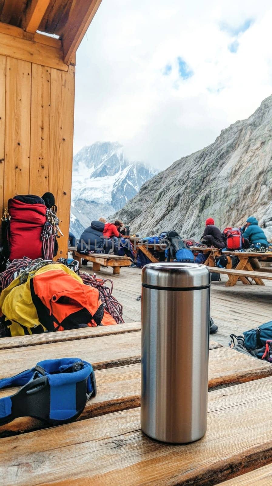 Climbers taking a break at a mountain hut, enjoying refreshments with a stunning view of snow capped peaks