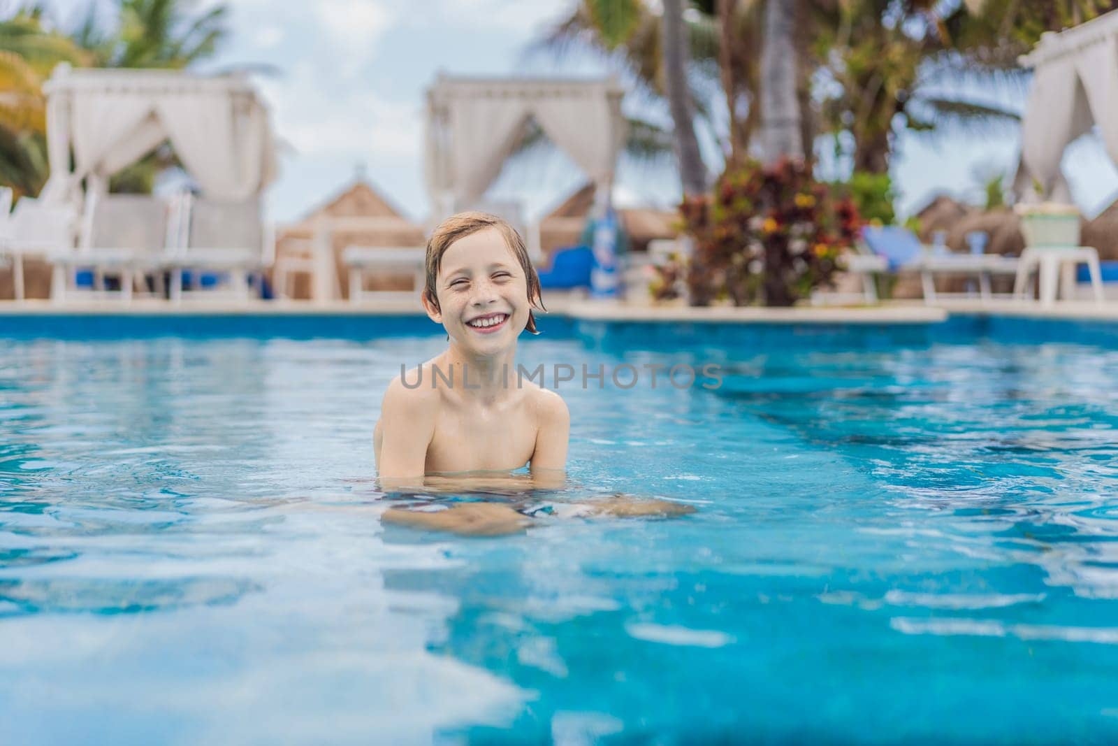 A young boy joyfully swims in a tropical pool surrounded by lush greenery. The vibrant scene captures the essence of summer fun, adventure, and carefree childhood moments in a refreshing outdoor setting.