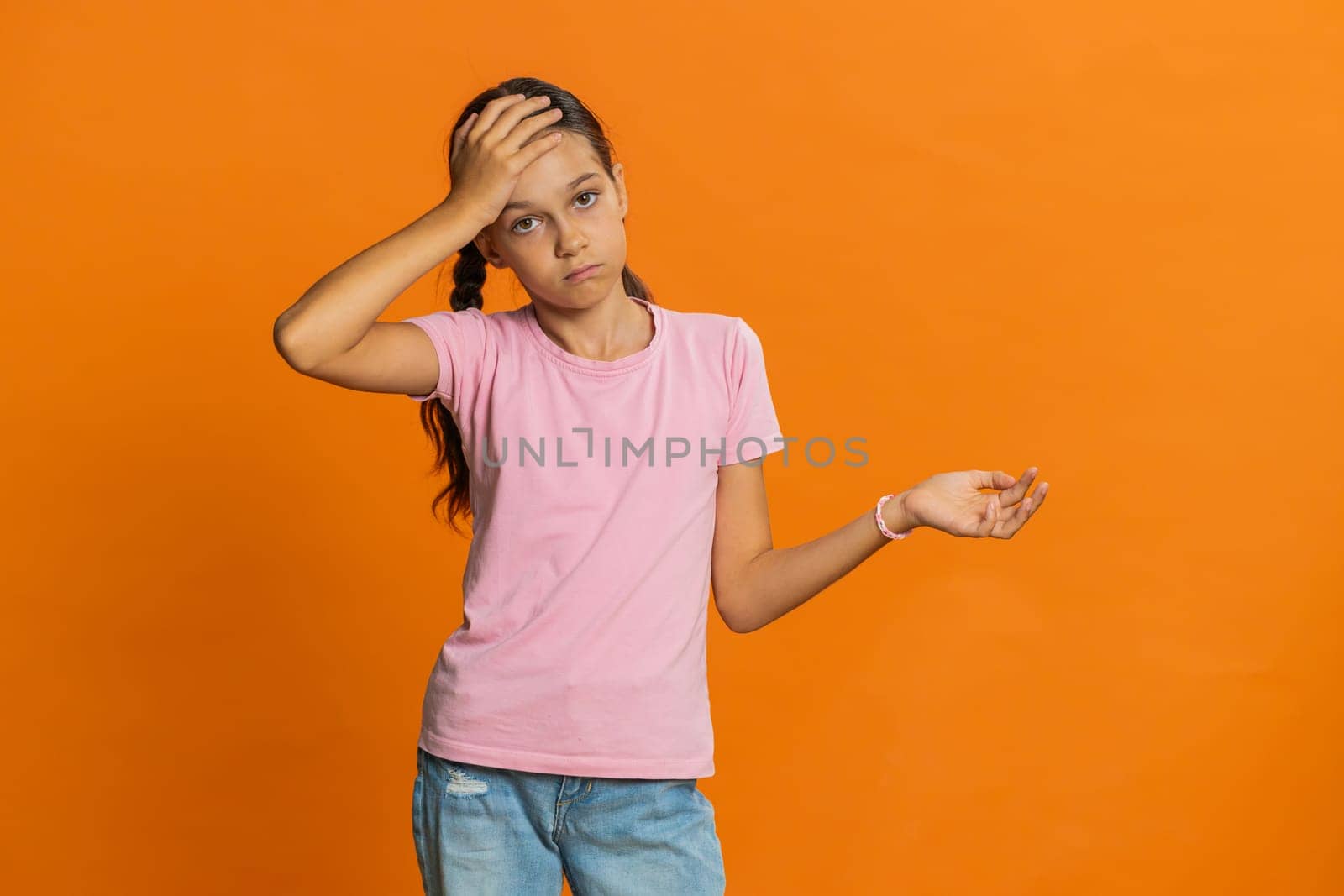 Face palm. Shame on you. Upset sad young preteen child girl kid making face palm gesture, feeling bored, disappointed in result, bad news, disagreement, quarrel. Teenager children on orange background