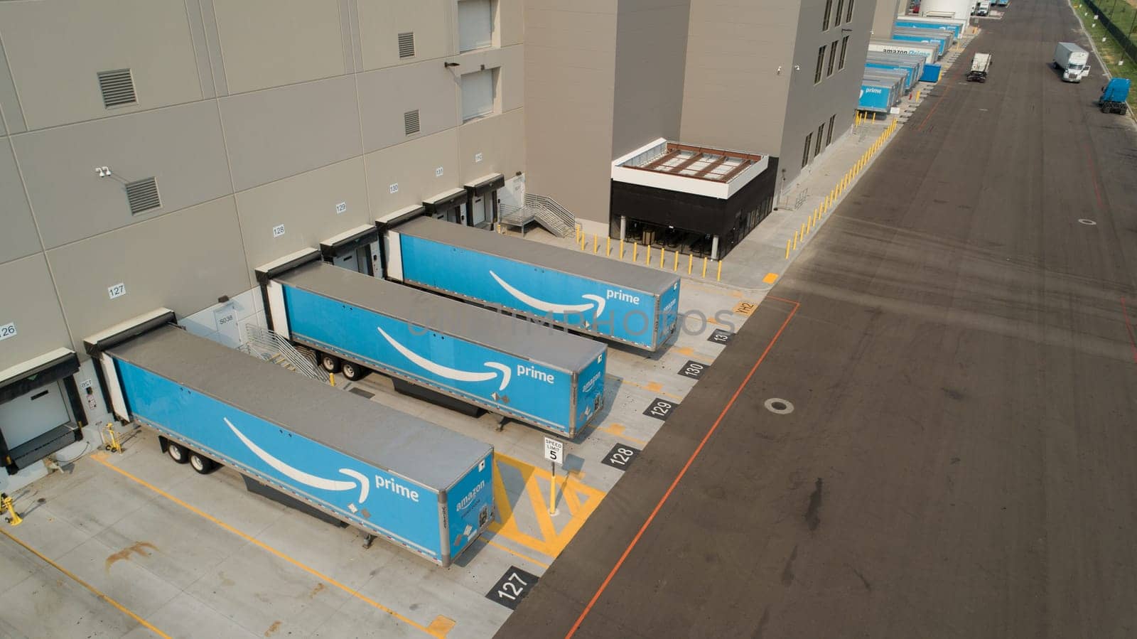 Nampa, Idaho - July 25, 2021: A large building with a lot of Amazon trucks parked in front of it. The trucks are blue and white