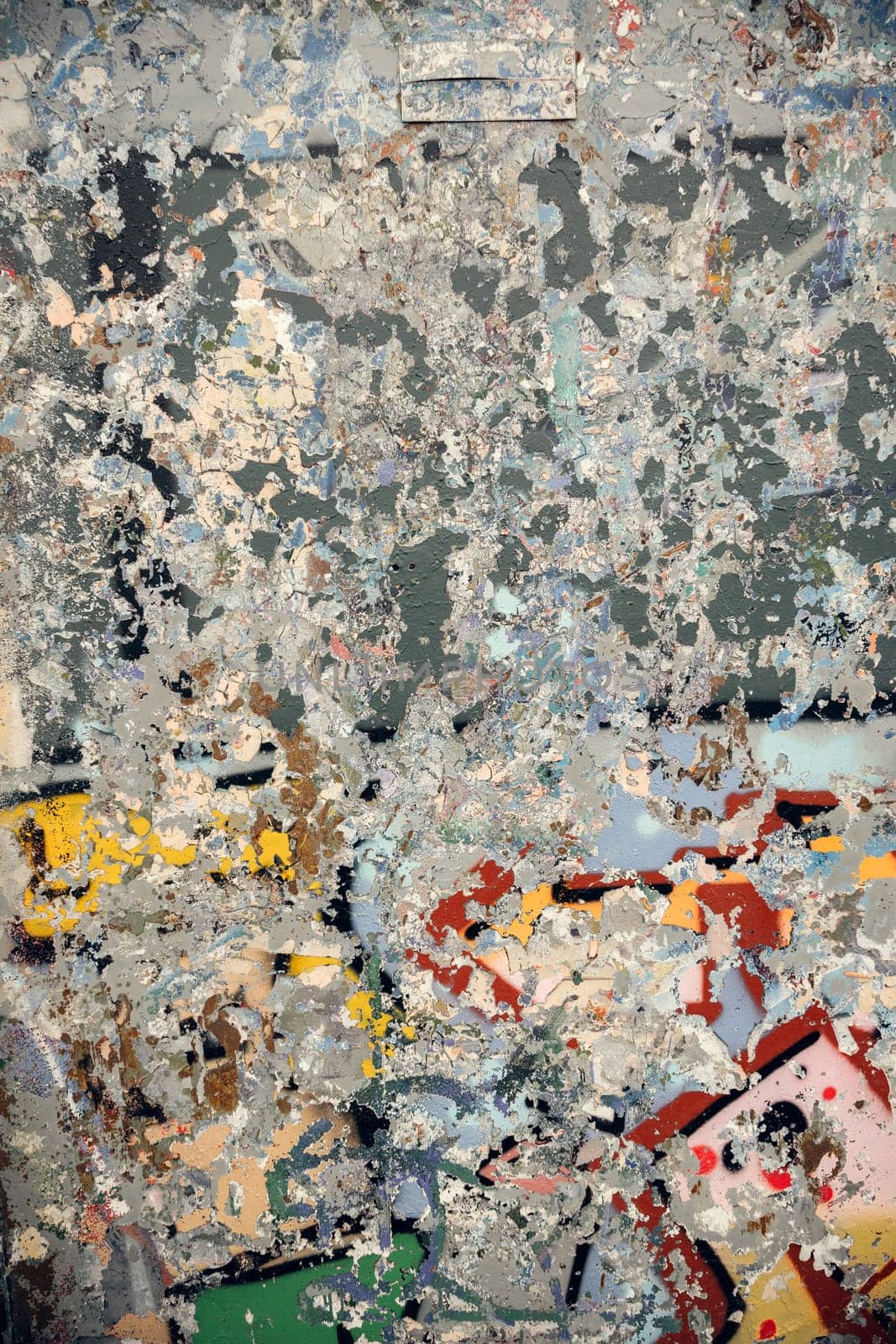 A close-up of a textured wall with cracked paint and graffiti remnants. The rough, layered surface adds depth and a grunge aesthetic, perfect for artistic backgrounds and digital designs.