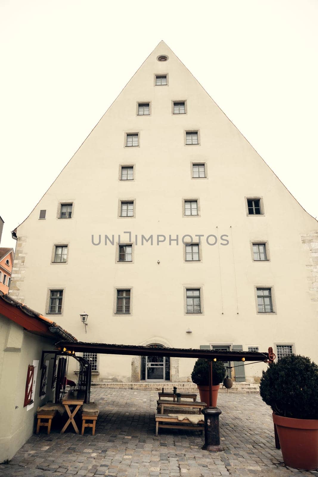 A historic triangular building with symmetrical windows and a cozy courtyard in Regensburg, Germany. A perfect setting for travel, architecture, and history-related projects.