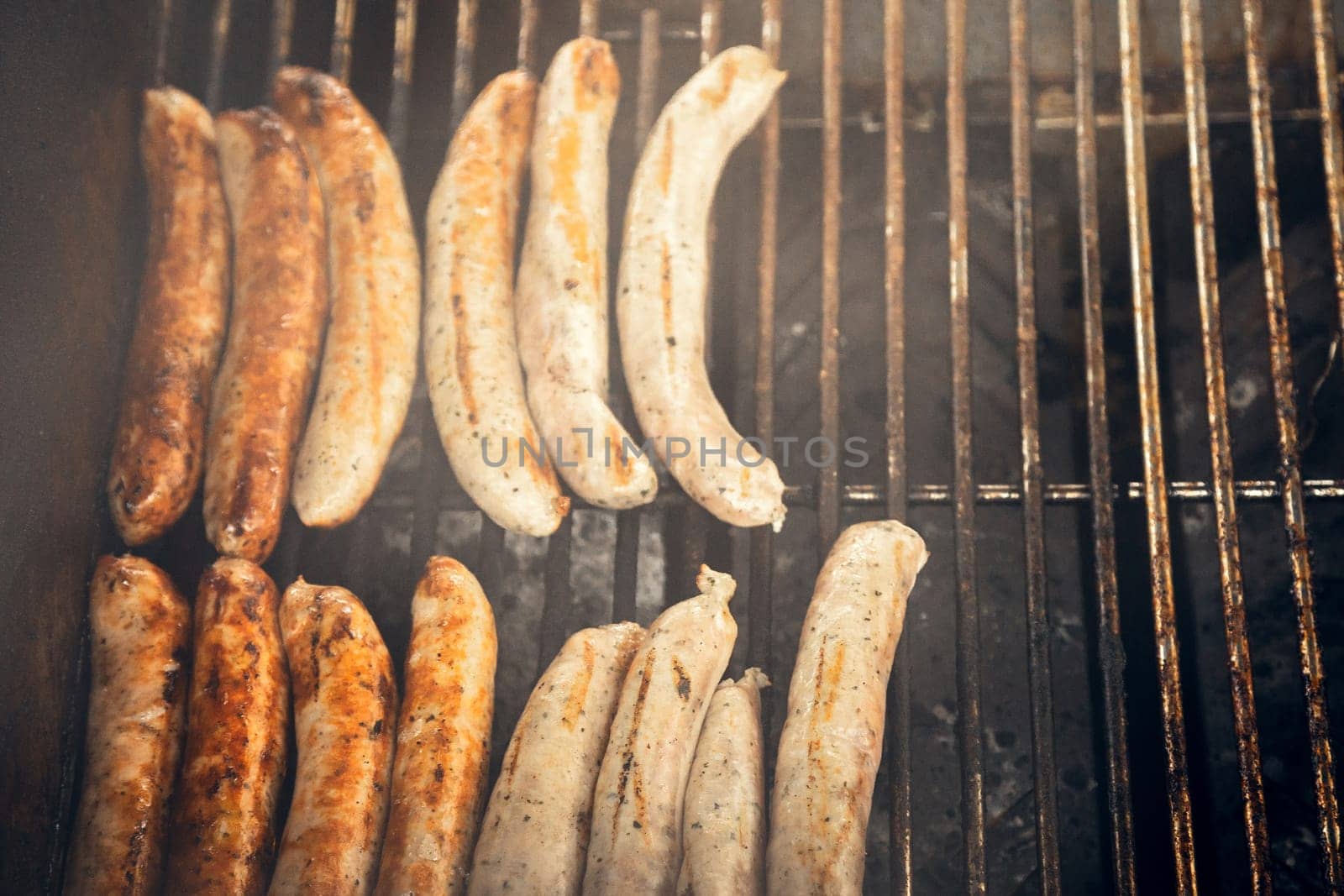 Sizzling sausages on a smoky barbecue, creating a rustic and appetizing scene. Ideal for food blogs, restaurant menus, barbecue-themed visuals, and outdoor cooking concepts