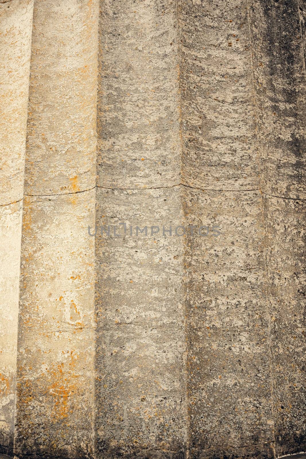 Old stone column showcasing vertical grooves and a rough, weathered texture. The aged surface and natural color variations make it ideal for backgrounds, architecture, and history-themed designs.