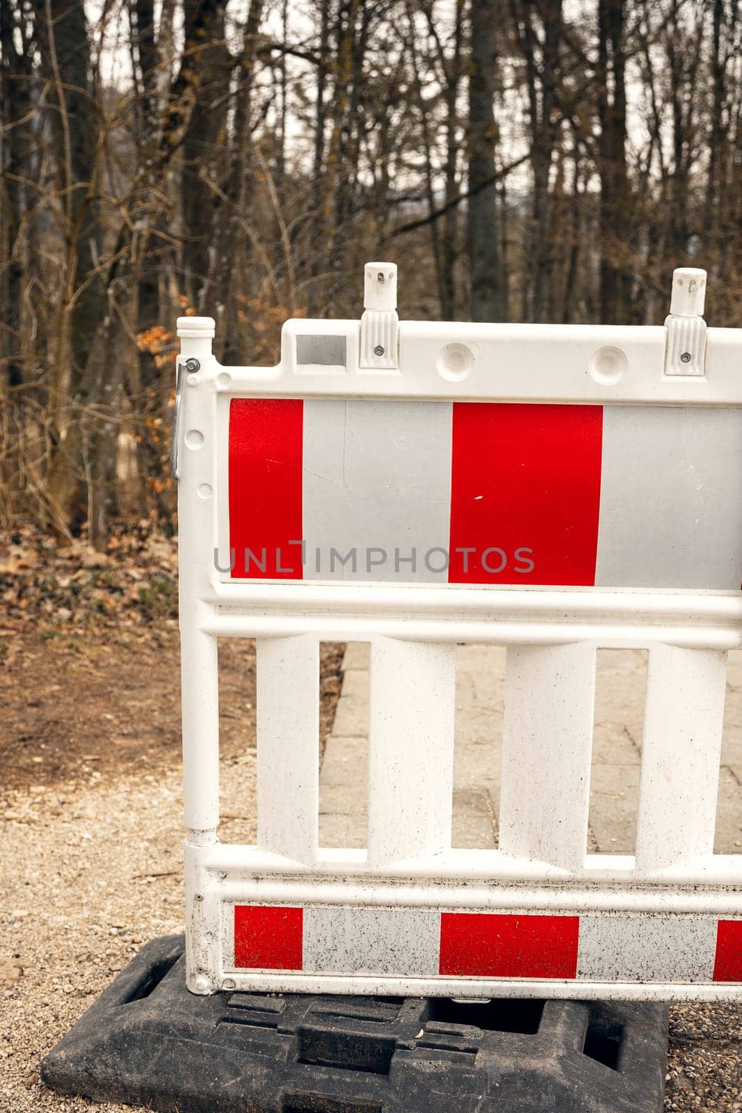 Red and white road barrier blocking a pathway in a forest. Construction or safety restriction in a natural setting. ideal for safety, construction, and warning-related visuals