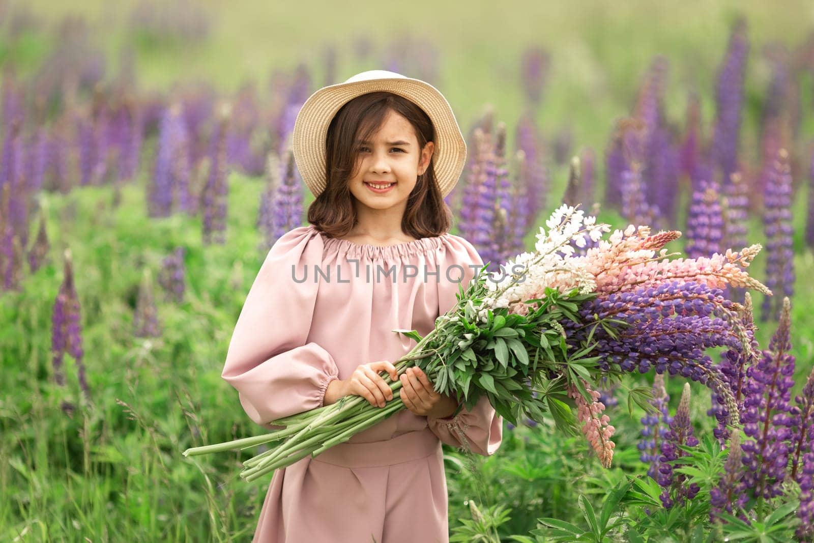 Smiling caucasian young girl in purple flower field holding bouquets.