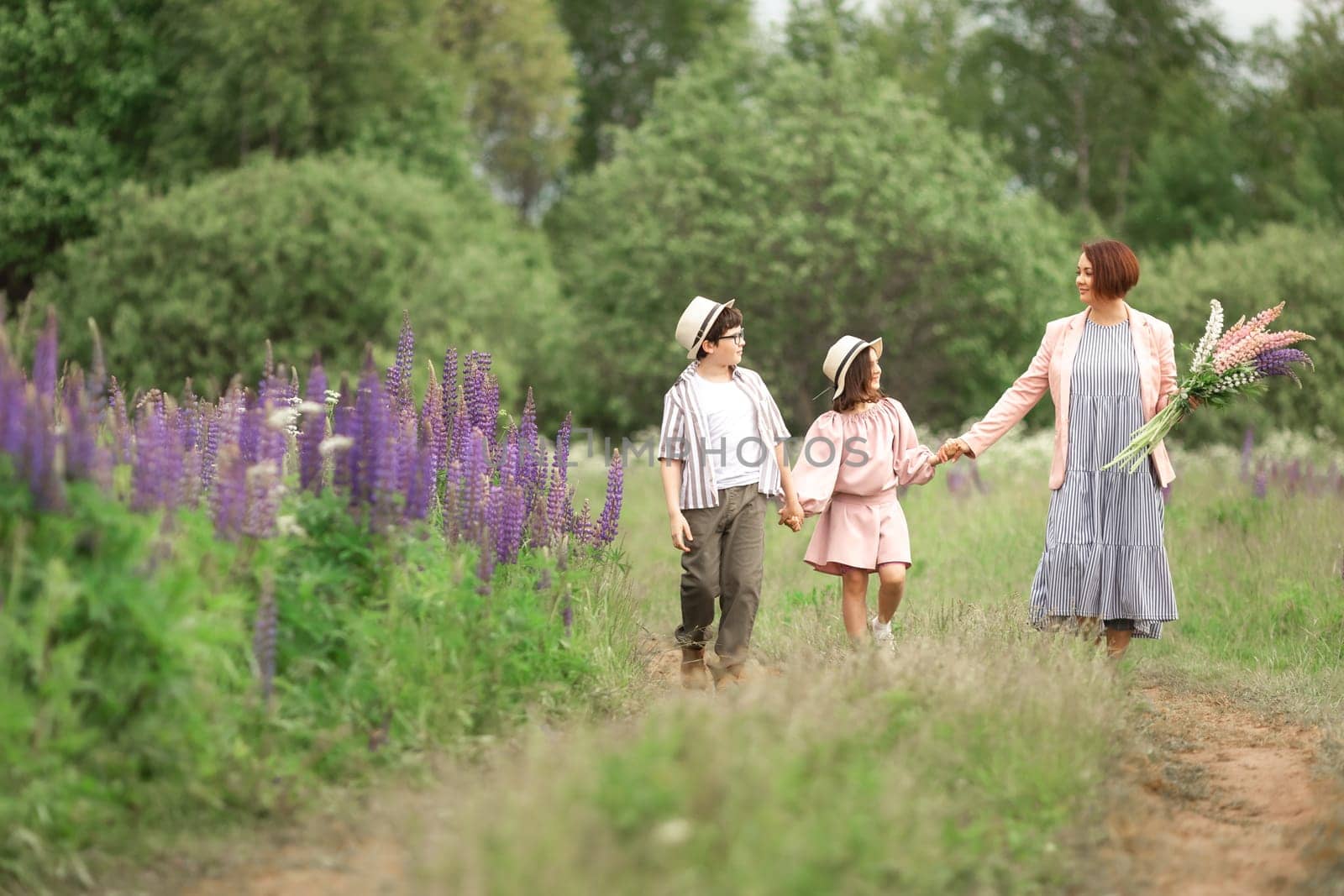 Caucasian family stroll: mother with son and daughter in nature holding flowers.