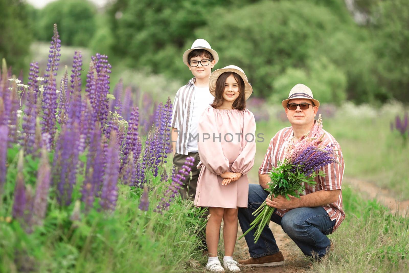 Caucasian family outdoors with adult male and children in flowers field.