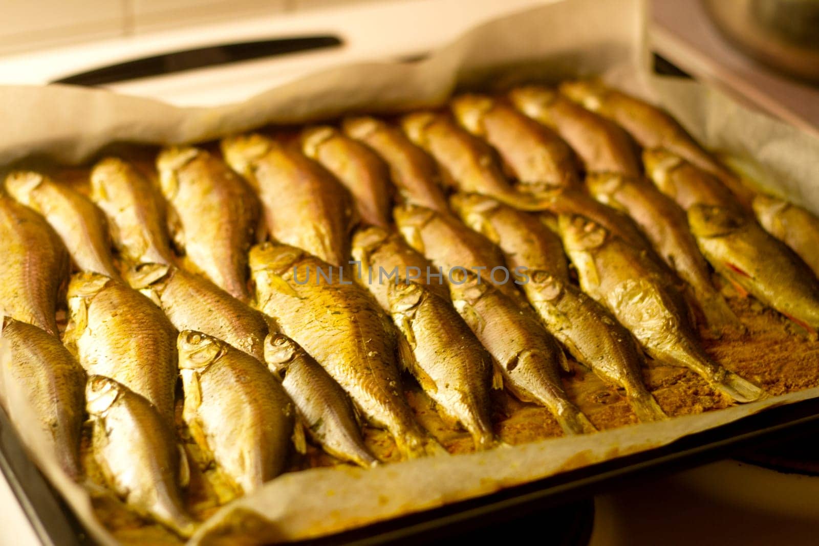 baked fish lies on a baking tray, food